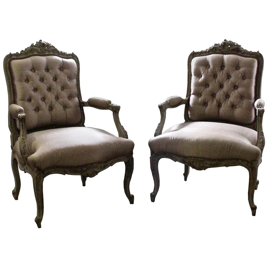 A pair of French Louis XV style carved and painted wood armchairs, circa 1860, painted wooden frames with carved floral decoration, upholstered in buttoned silk.