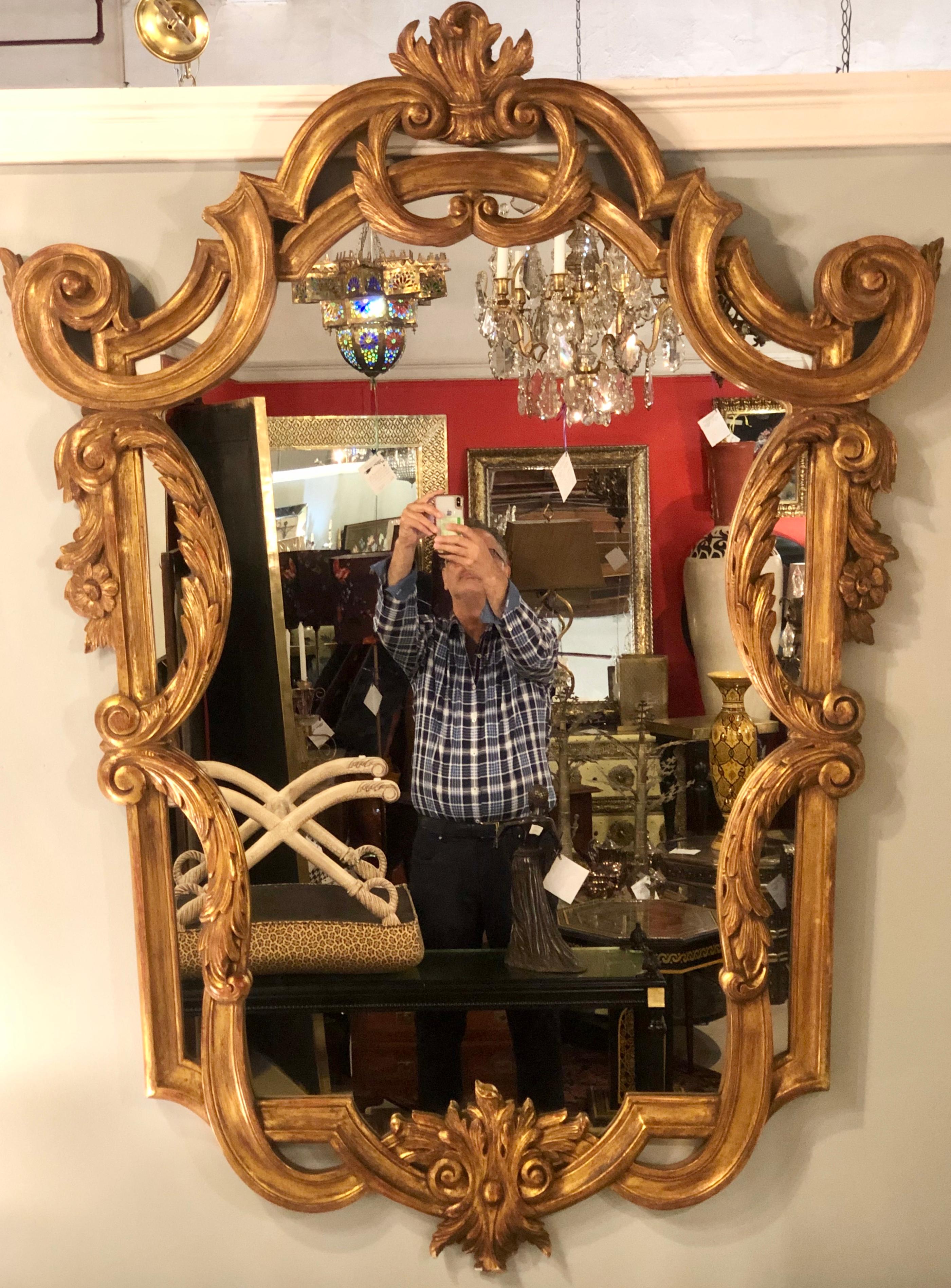 Pair of Louis XV style console, pier or wall mirrors. Giltwood carved frames that are second to none on these large and impressive wall or console mirrors. The pair with roses, scrolls and vines carved terminating in a flame finial.