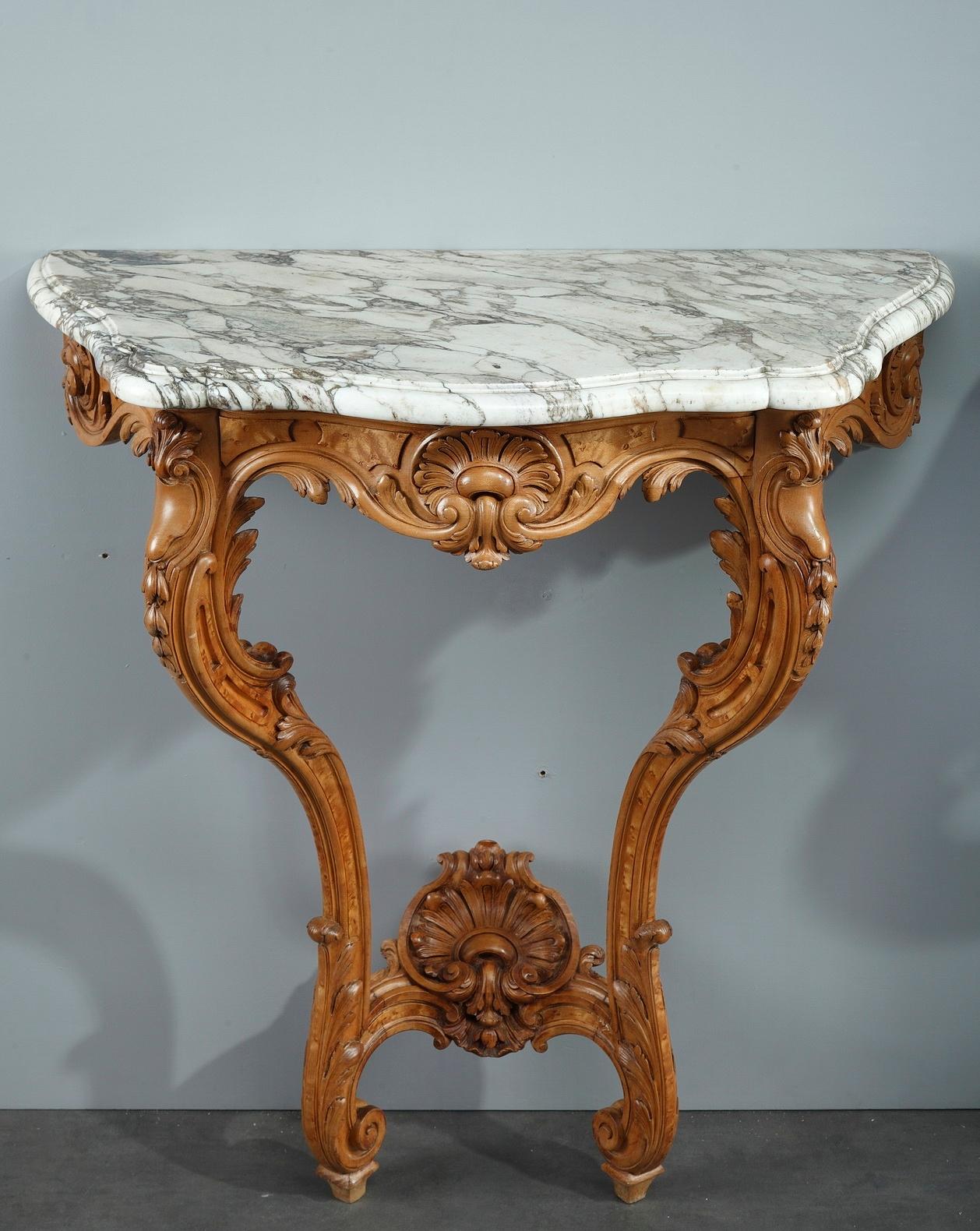 Un par de consolas de inspiración Luis XV fabricadas en madera de olmo natural maravillosamente tallada. Las conchas marinas naturalistas y las hojas de acanto con volutas ilustran perfectamente el gusto Luis XV, muy apreciado bajo Napoleón III