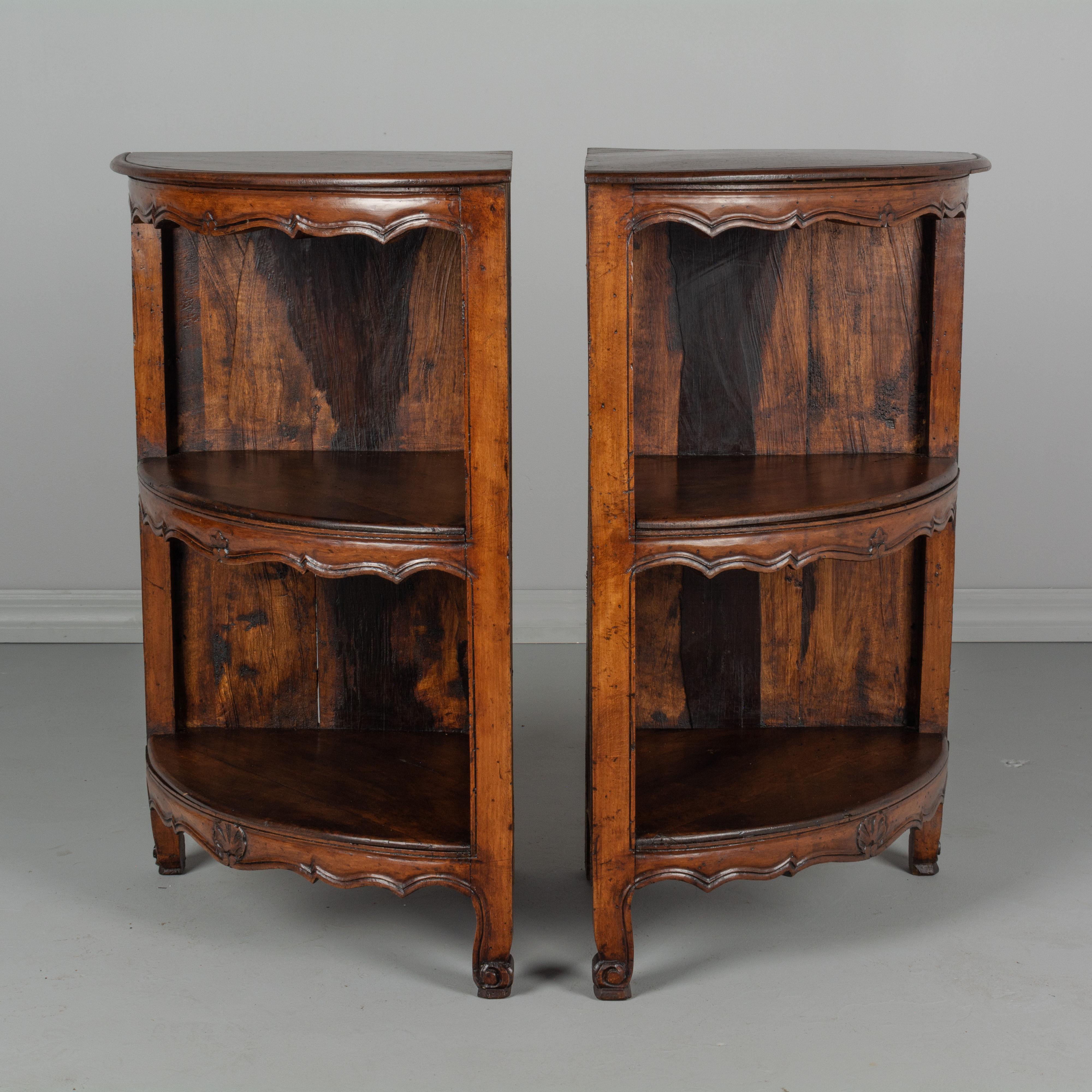 A pair of Country French Louis XV style corner shelves made of walnut with hand-carved decoration and scroll toes. A versatile pair of side tables that may be used as a small console when drawn together, or as small bedside tables when separated.