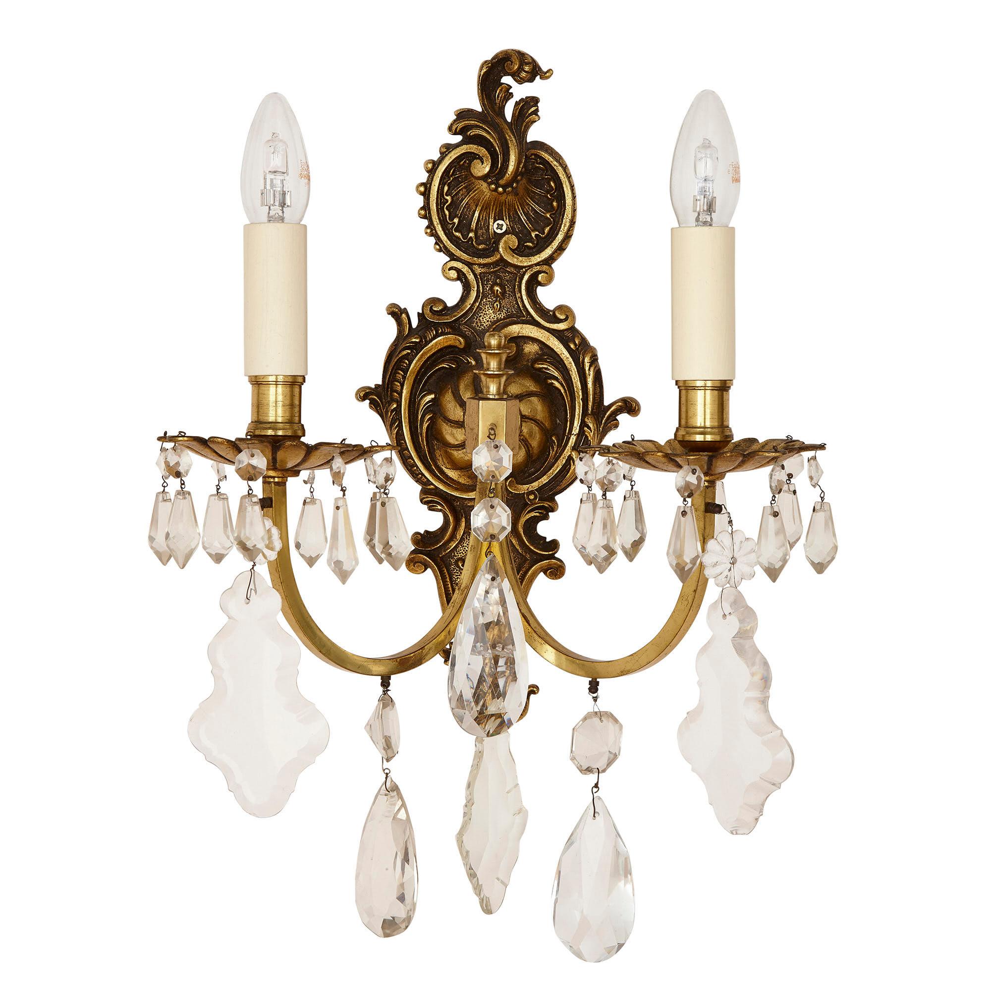 Pair of Louis XV style cut glass sconces
French, early 20th century
Measures: Height 46cm, width 34cm, depth 21cm

The sconces in this pair are wrought from gilt metal in the Louis XV style. Each sconce features a shaped backplate moulded with