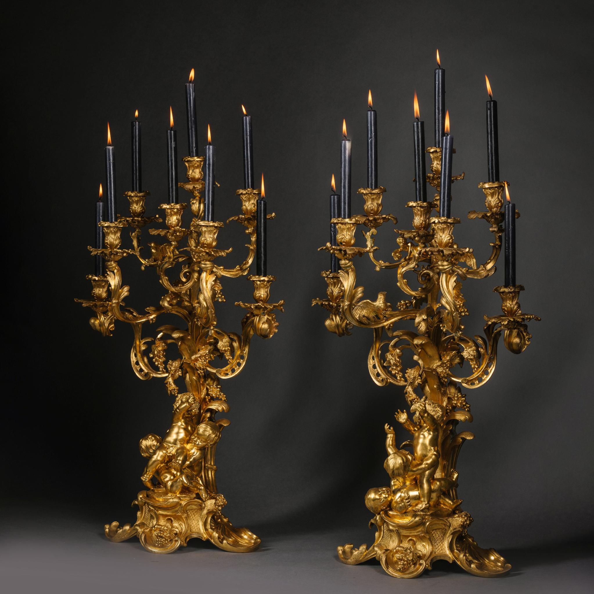 Ein Paar vergoldeter Bronzekronleuchter im Stil Louis XV, Victor Paillard zugeschrieben.

Sie sind überschwänglich im Stil des Rokoko modelliert und zeigen verspielte Putten, die Trauben von einem Baum pflücken. Die verschnörkelten und