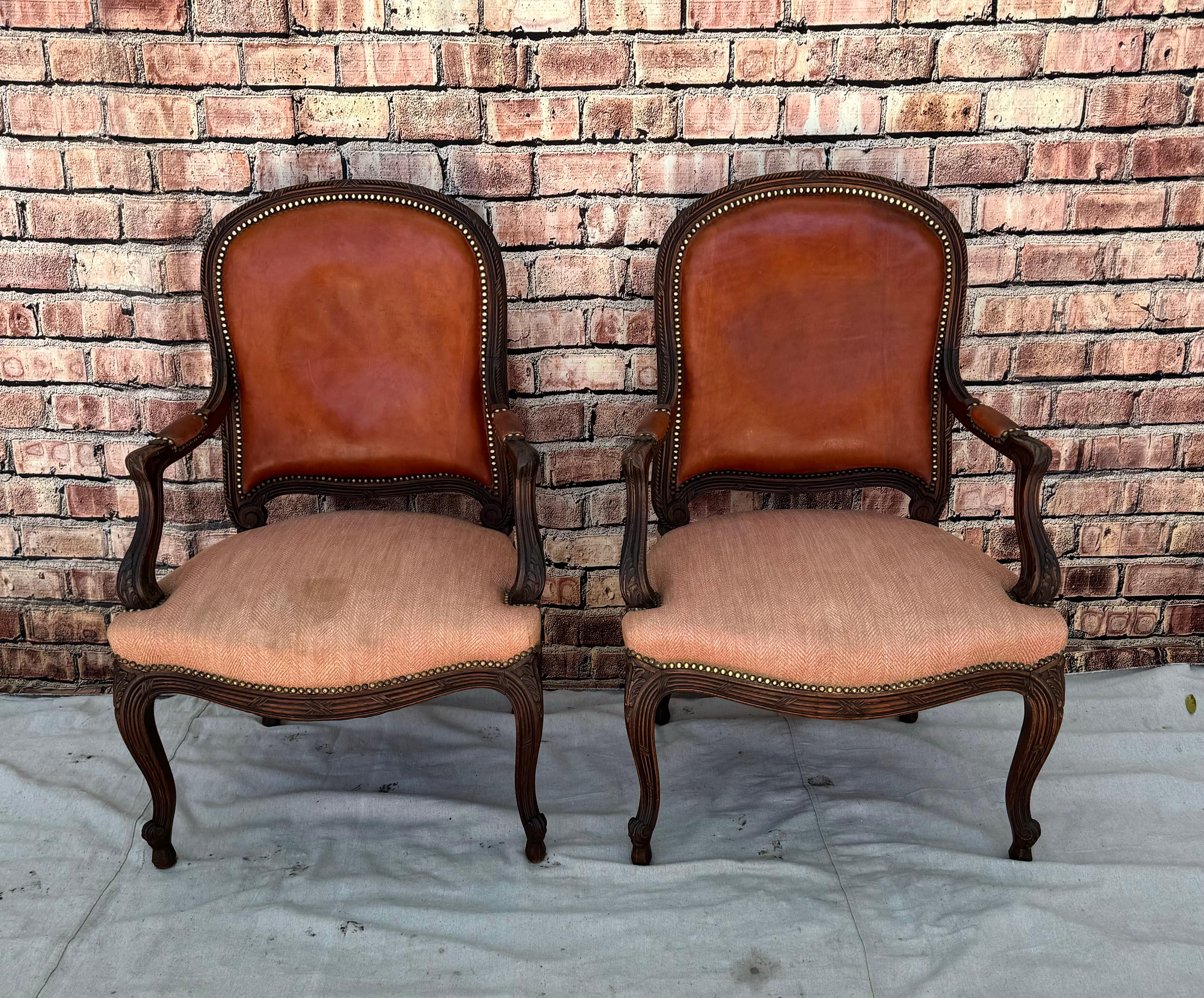 Pair of Louis XV Style Fauteuil armchairs. Chairs feature carved and shaped walnut frames, a serpentine skirt, and carved cabriole legs. Chairs also feature tacked red leather backs and arm rests with chevron pattern cloth seats. Nice accent chairs