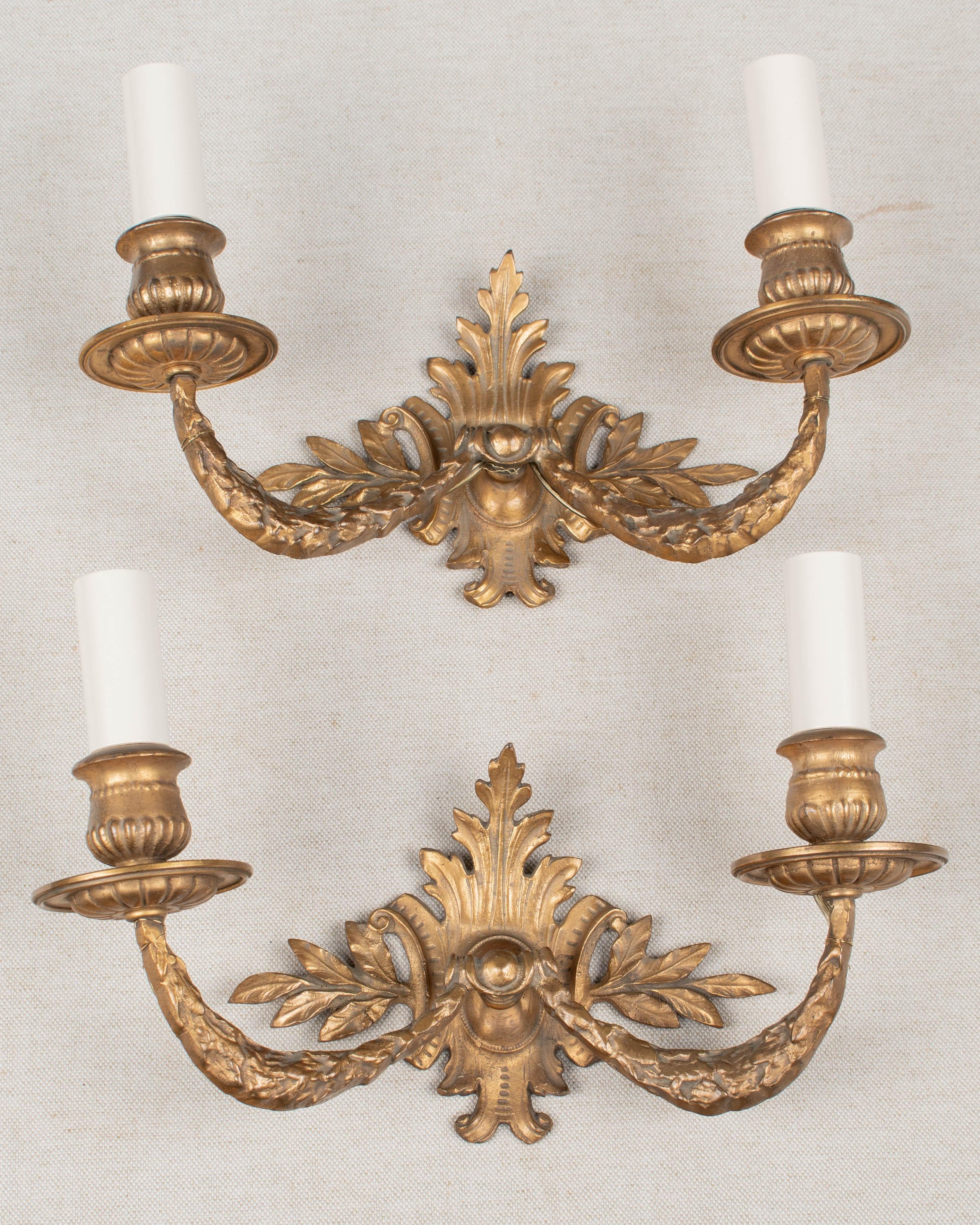A pair of Louis XV style French two-light cast bronze sconces. Nice quality casting with original patina. Rewired, new sockets and candle covers. Circa 1900-1920. 
Dimensions: 10.25
