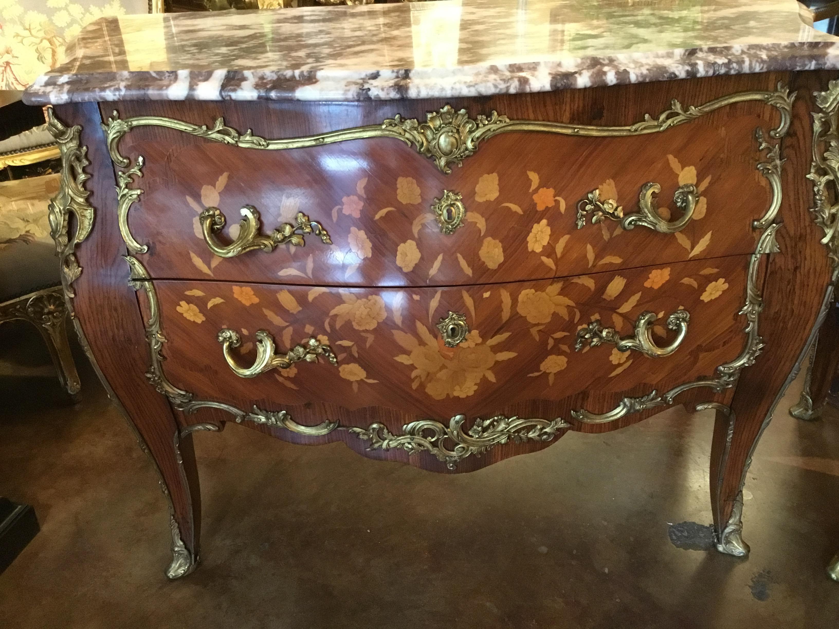Exquisite pair of French commodes with bronze dore mounts and marquetry inlay.
Bombe form with graceful curved leg ending in sabots. The cabinets are made of
Kingwood and have satinwood inlay. The marble tops are beige with pale mauve hues.