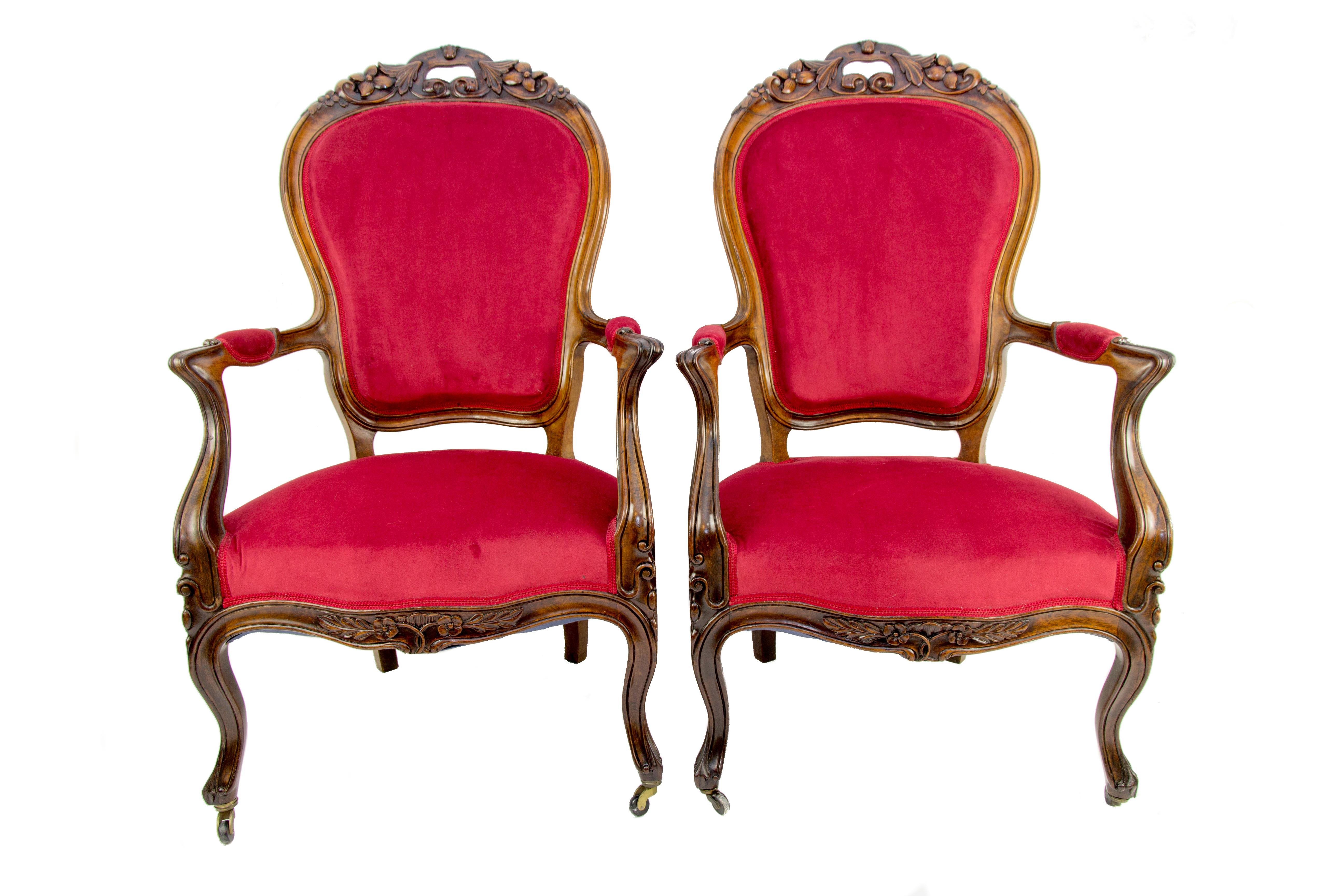 Pair of Louis XV style armchairs or fauteuils from the late 19th century is made of walnut wood, with an upholstered seat, armrests, and a backrest, decorated with beautiful floral carvings. The front legs of the armchairs are cabriole, on rollers.