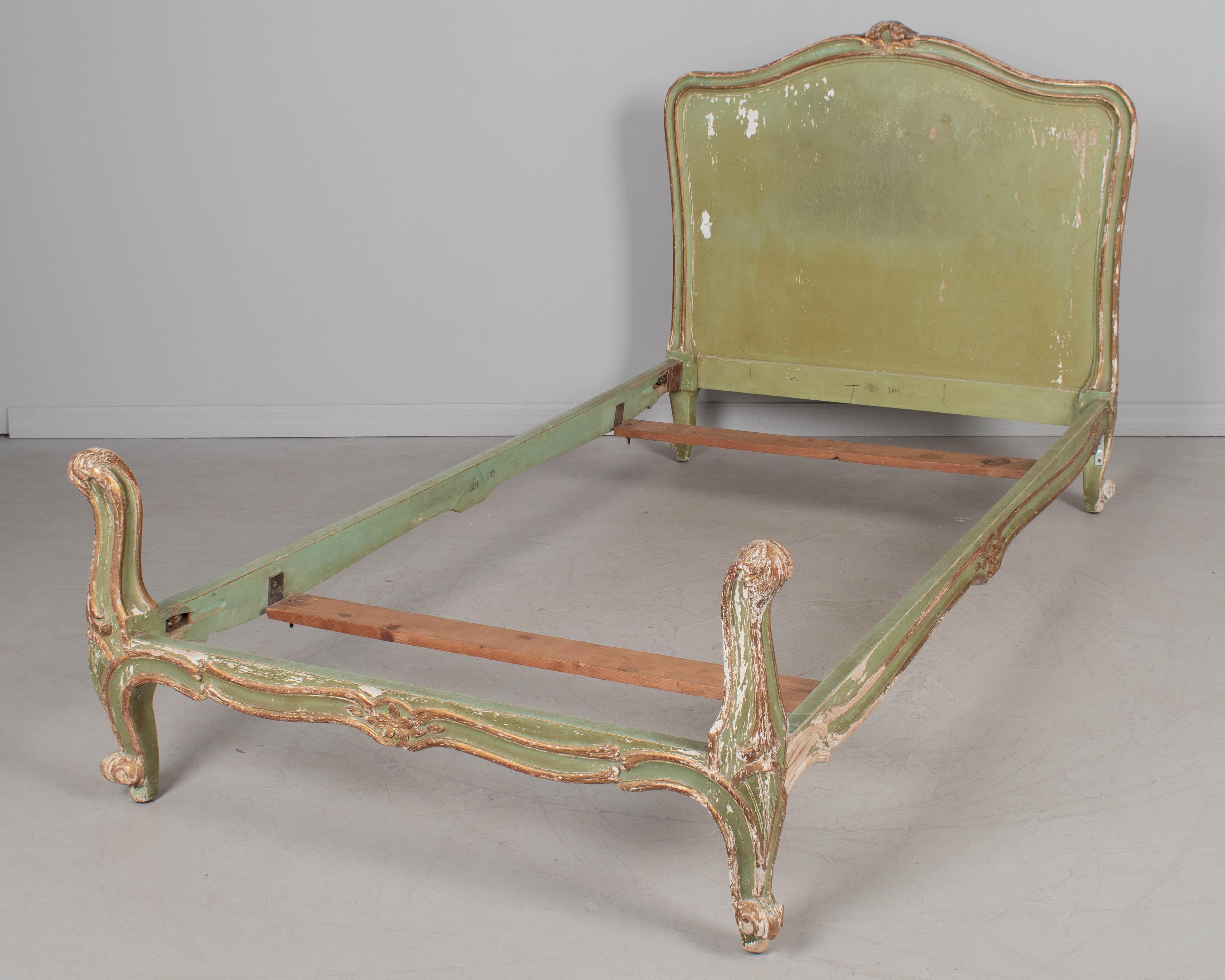 A pair of early 20th century French Louis XV style green painted twin size bed frames. Nicely detailed with carved flower decoration and gilt trim. Sturdy frames with some paint loss. Stamped Made in France on side rail. Good quality Stearns and