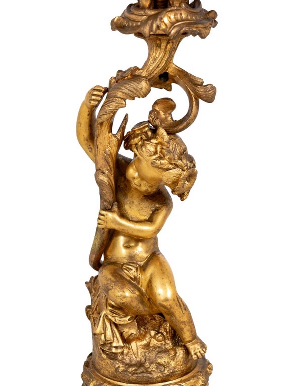 Coppia di candelabri a sei rami in bronzo dorato in stile Luigi XV, fine del XIX secolo, ciascuno con un cherubino seduto che sostiene dei rami fogliati, su una base a volute d'acanto e un plinto ottagonale ebanizzato, formalmente montati come