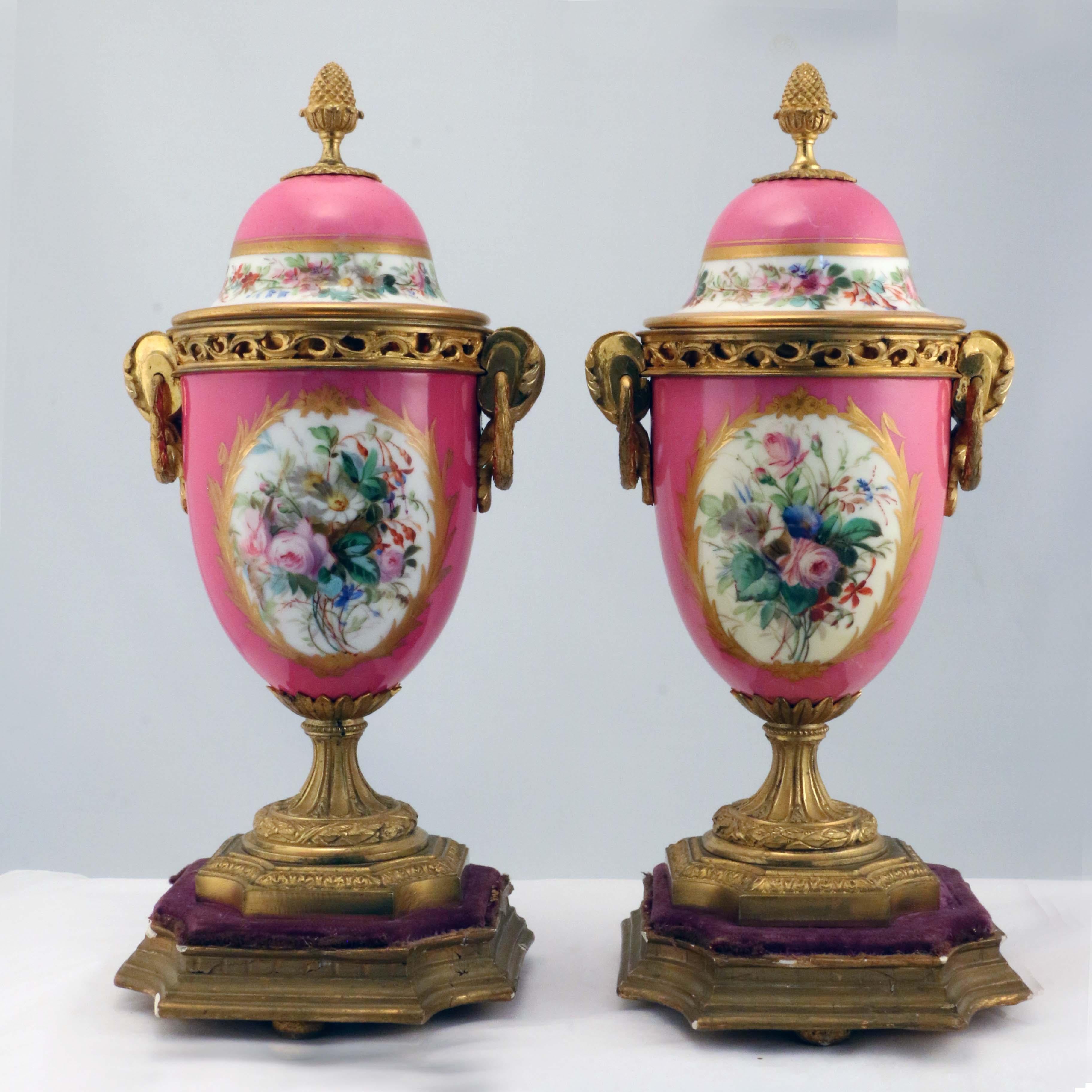 This pair are charmingly painted in oval reserves with mother and child within a gilt jeweled border, and verso with wild flowers. Each domed cover is painted correspondingly with a band of wild flowers and set with a bronze pineapple finial,