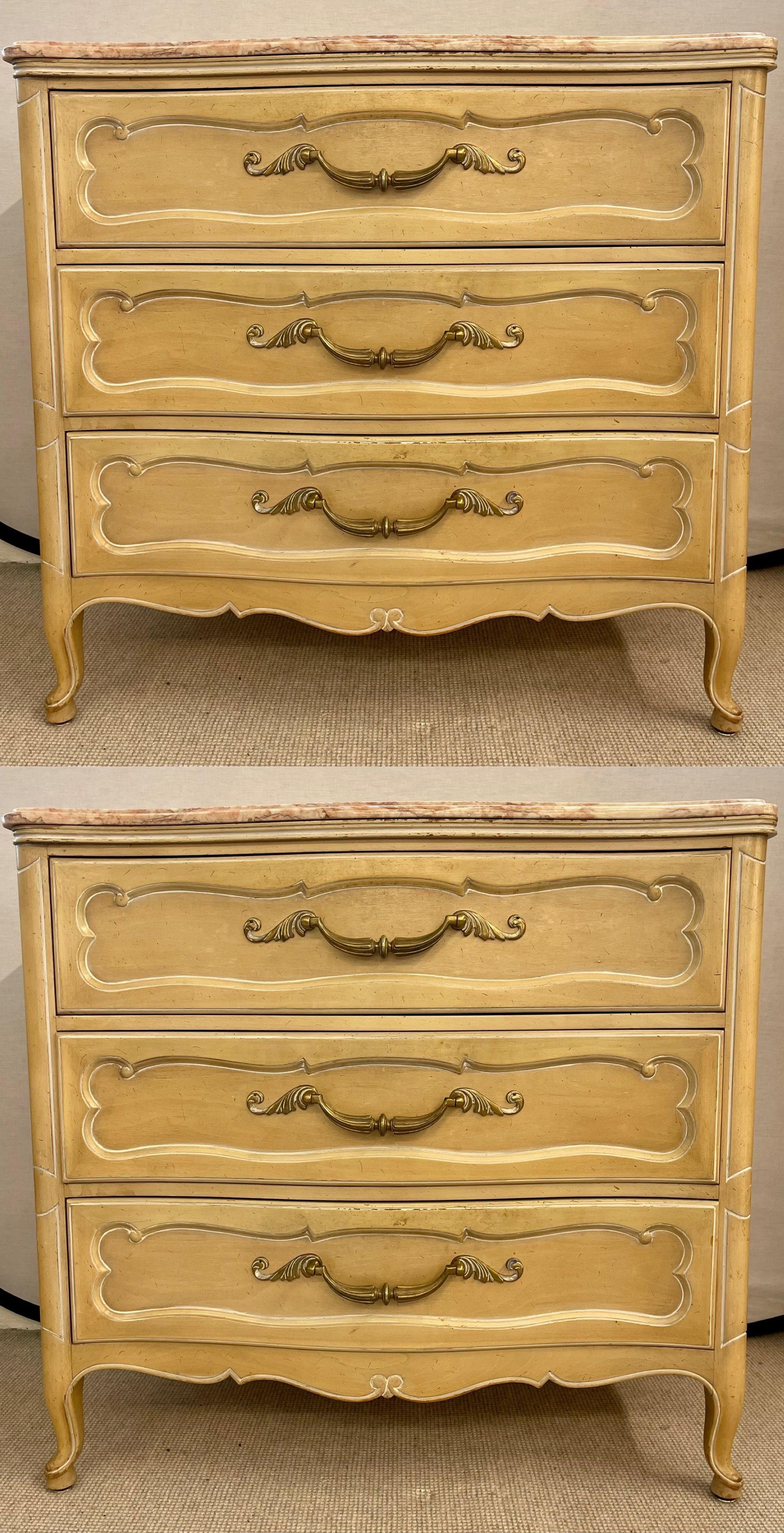 Louis XV style Grosfeld House marble-top four-drawer commodes. All drawers are lined. The color is a distressed cream wood, the pulls being brass. Fabulous rose and crème colored marble tops. Exquisite design.