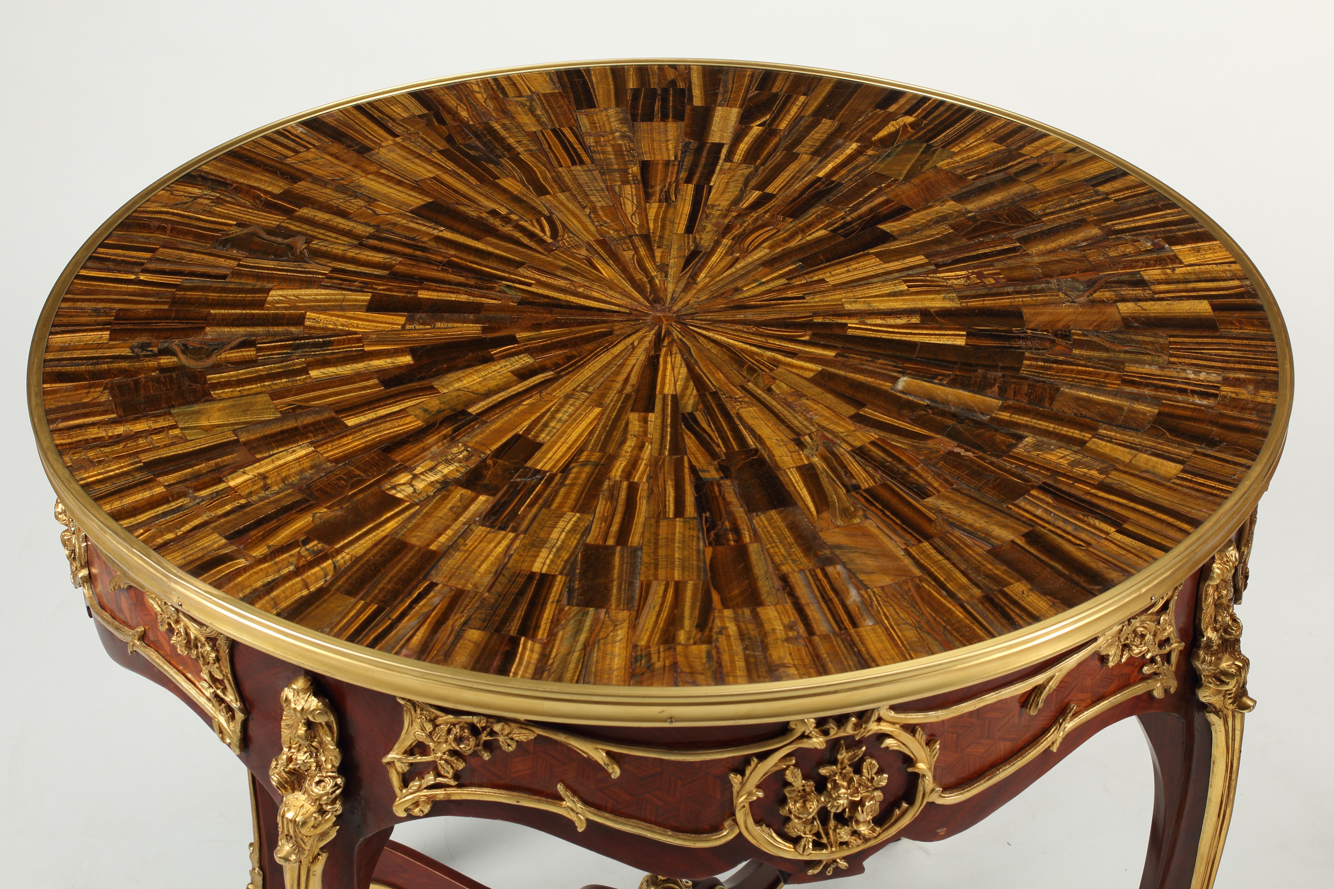 Une paire remarquable de Guéridons de style Louis XV avec des yeux de tigre rayonnants et des dessus de cadres ronds en laiton. Exceptionnellement détaillé avec des détails floraux et de feuillage. Placage de parquet vintage incrusté dans du bois