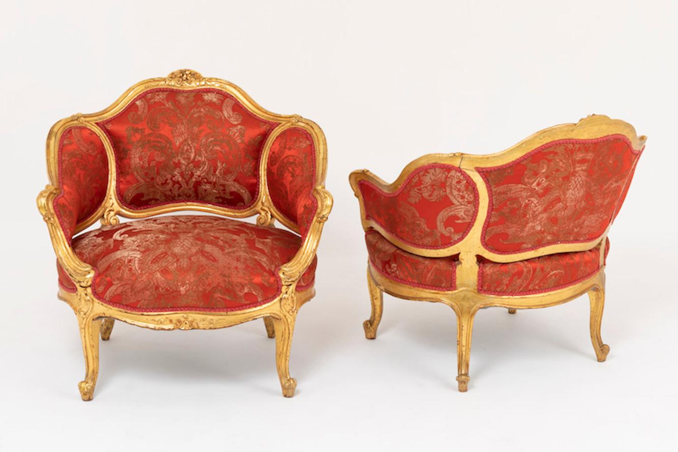 Pair of Louis XV style low bergeres in carved and giltwood standing on four small cabriole legs adorned with cartouches and finished by scrolls. Scalloped apron adorned in its centre by flowers and foliage.
Armrest supports in the legs lines with a