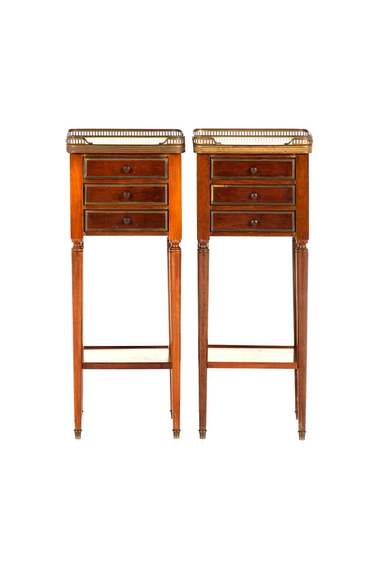 Magnifique paire de tables de chevet en acajou de style Louis XV avec dessus en marbre blanc.

Les plateaux sont entourés de simples galeries en laiton et comportent trois tiroirs avec des poignées en laiton complétées par des incrustations en
