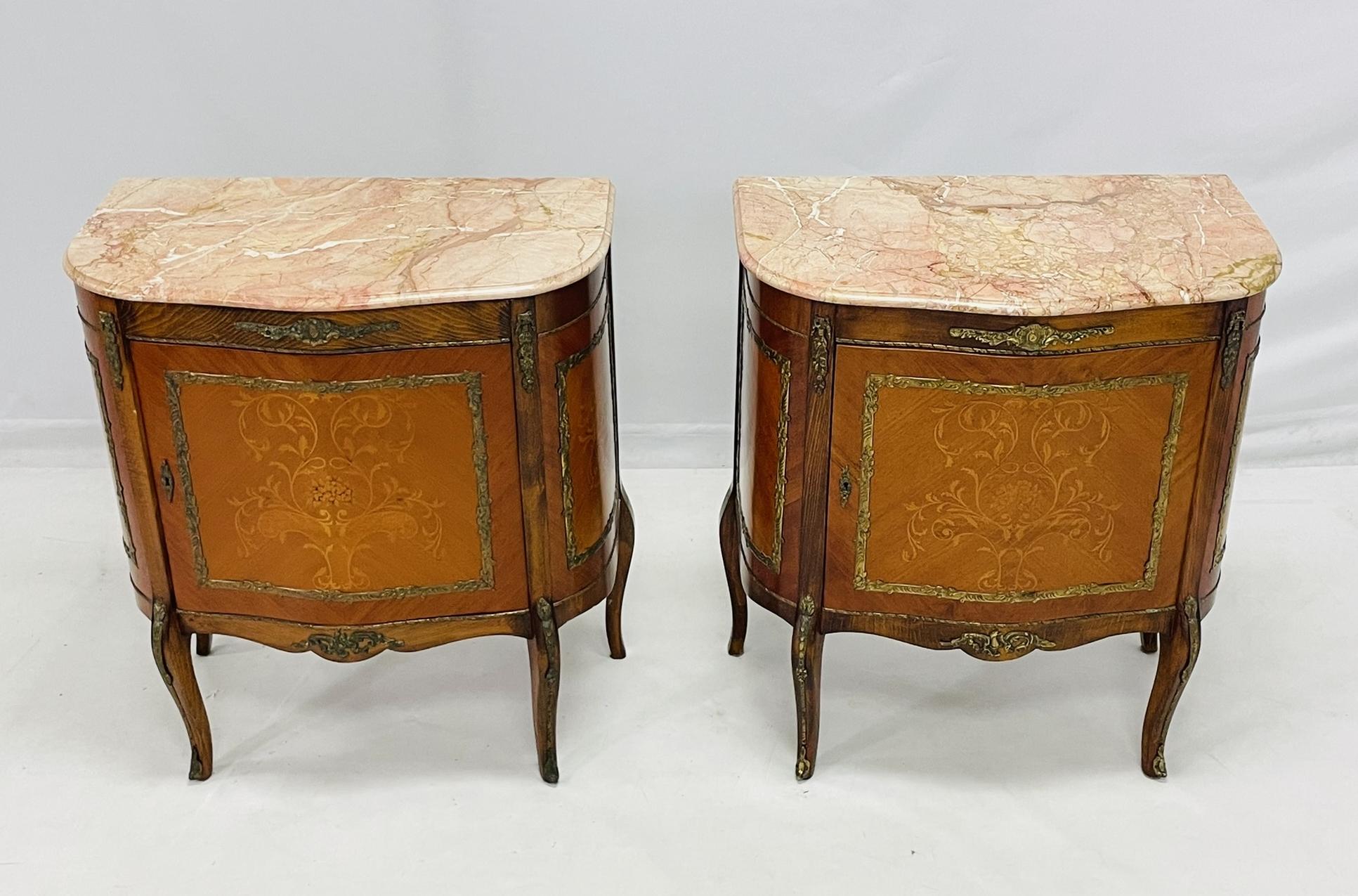 Un par de cómodas de estilo Luis XV finamente trabajadas, fabricadas en Rumanía hacia 1980, marcadas C 455, NOE. Cada mueble presenta una encimera de mármol rosa perfilado con suaves vetas, que descansa sobre un frente serpenteante con un solo cajón