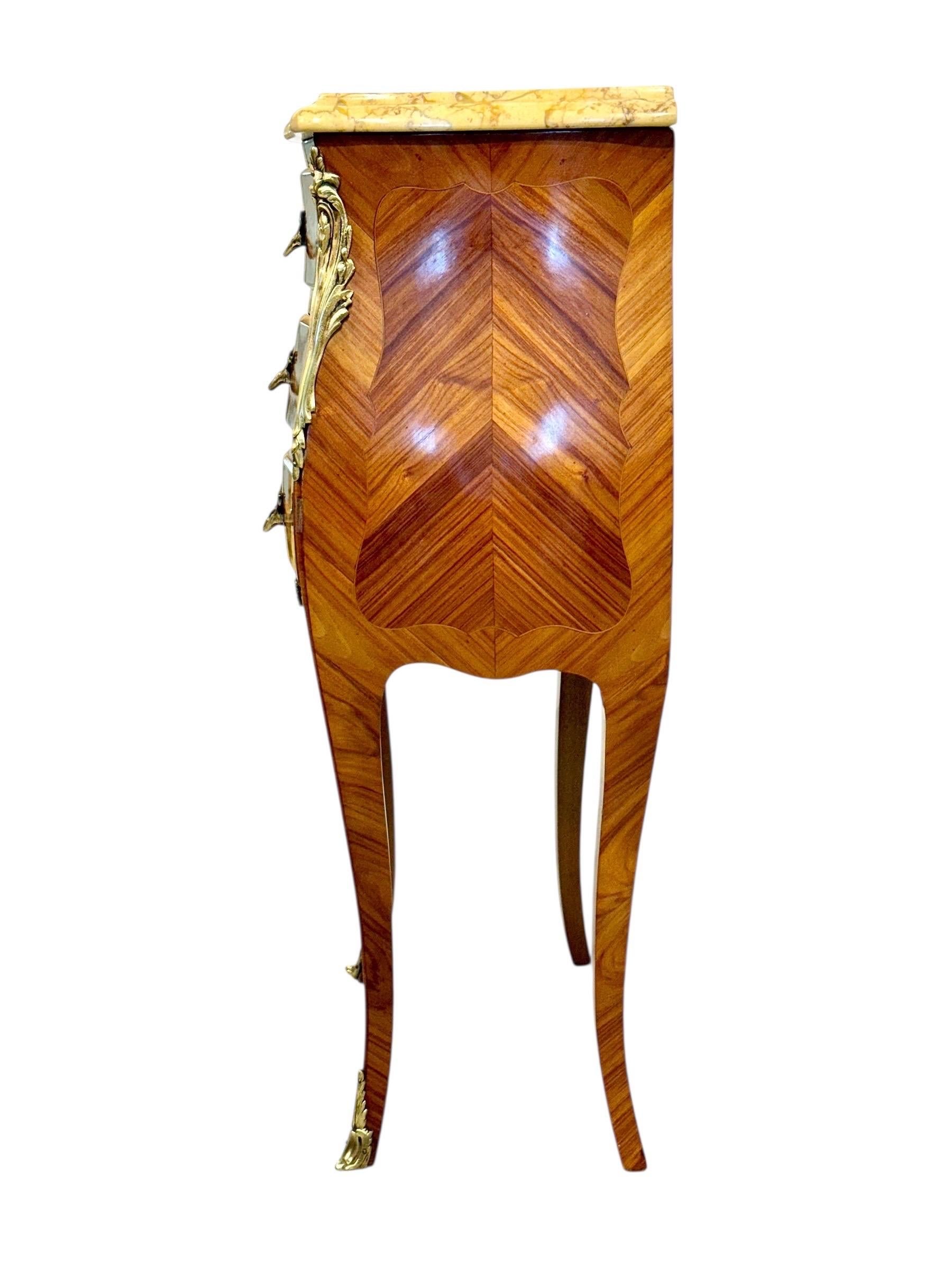 Cette élégante paire de tables de chevet de style Louis XV, datant du début du XXe siècle (vers 1920), incarne magnifiquement le raffinement de l'artisanat français. Chaque table est finement plaquée de bois richement figurés disposés selon un