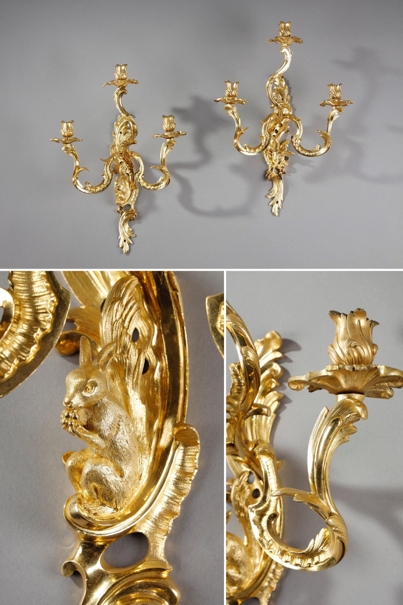 Pair of ormolu three-light sconces in the Louis XV style. The sconces are finely carved and chased with acanthus leaves and scrolling foliage. This rich, eventful decoration is typical of the Rocaille style, which flourished in France during the