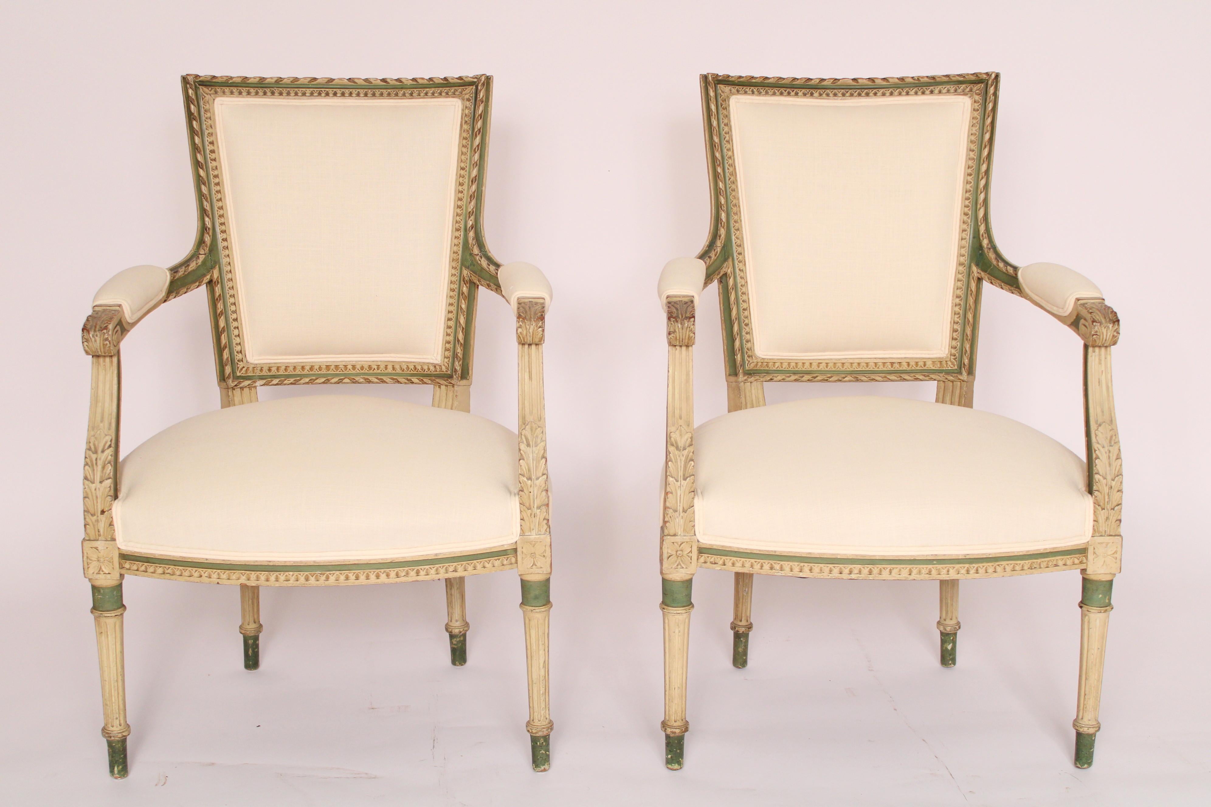 Pair of Louis XVI style painted armchairs, circa 1920. With rope carved trapezoid shaped backs, armrest ending with acanthus carvings, down swept fluted and acanthus carved arm supports, upholstered seats resting on turned tapered fluted legs.