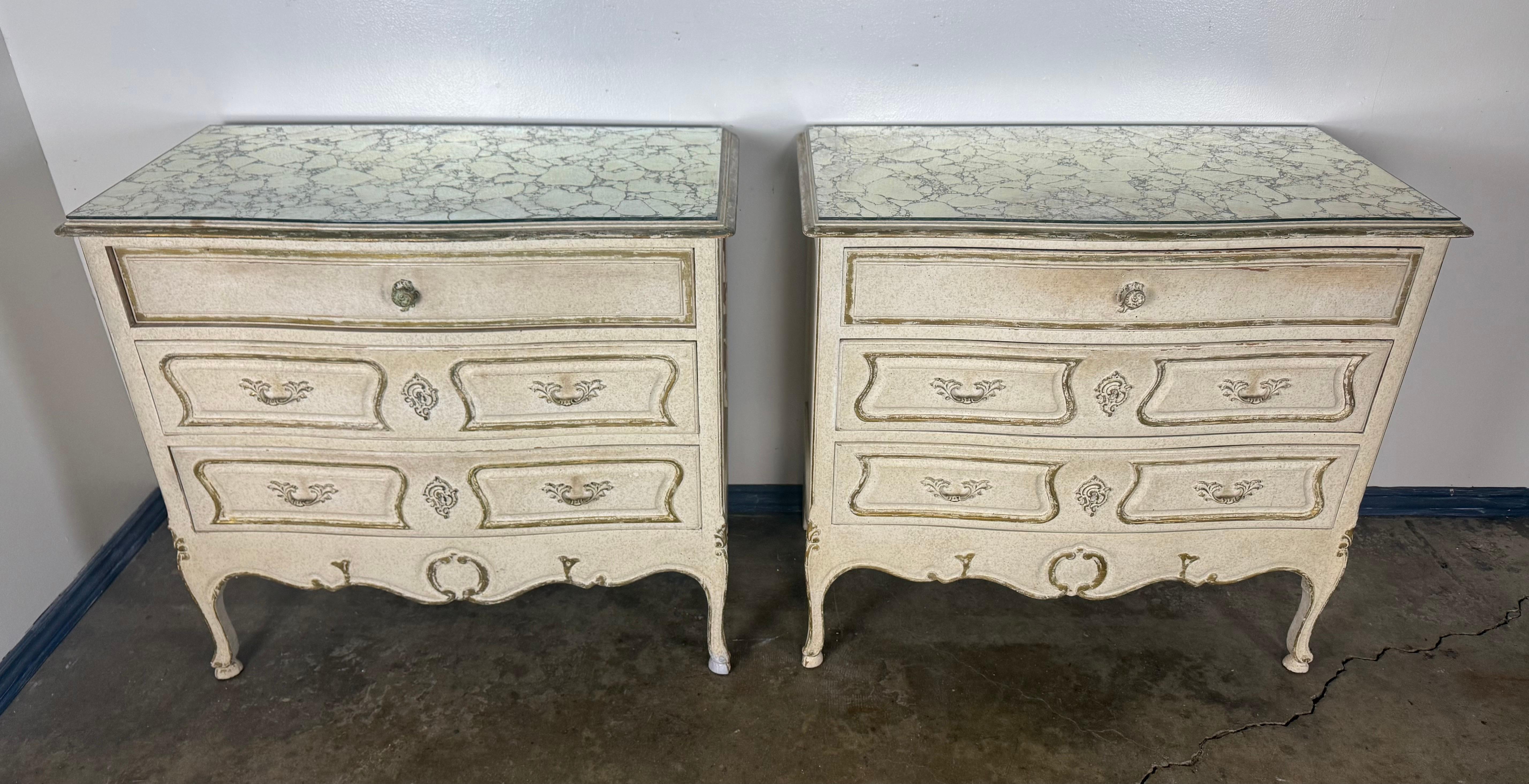 Una graziosa e raffinata coppia di cassapanche dipinte in stile Luigi XV, rifinite in un morbido crema patinato con accenti dorati e sormontate da splendidi specchi anticati che hanno sviluppato un motivo foxing riccamente marmorizzato. Le superfici