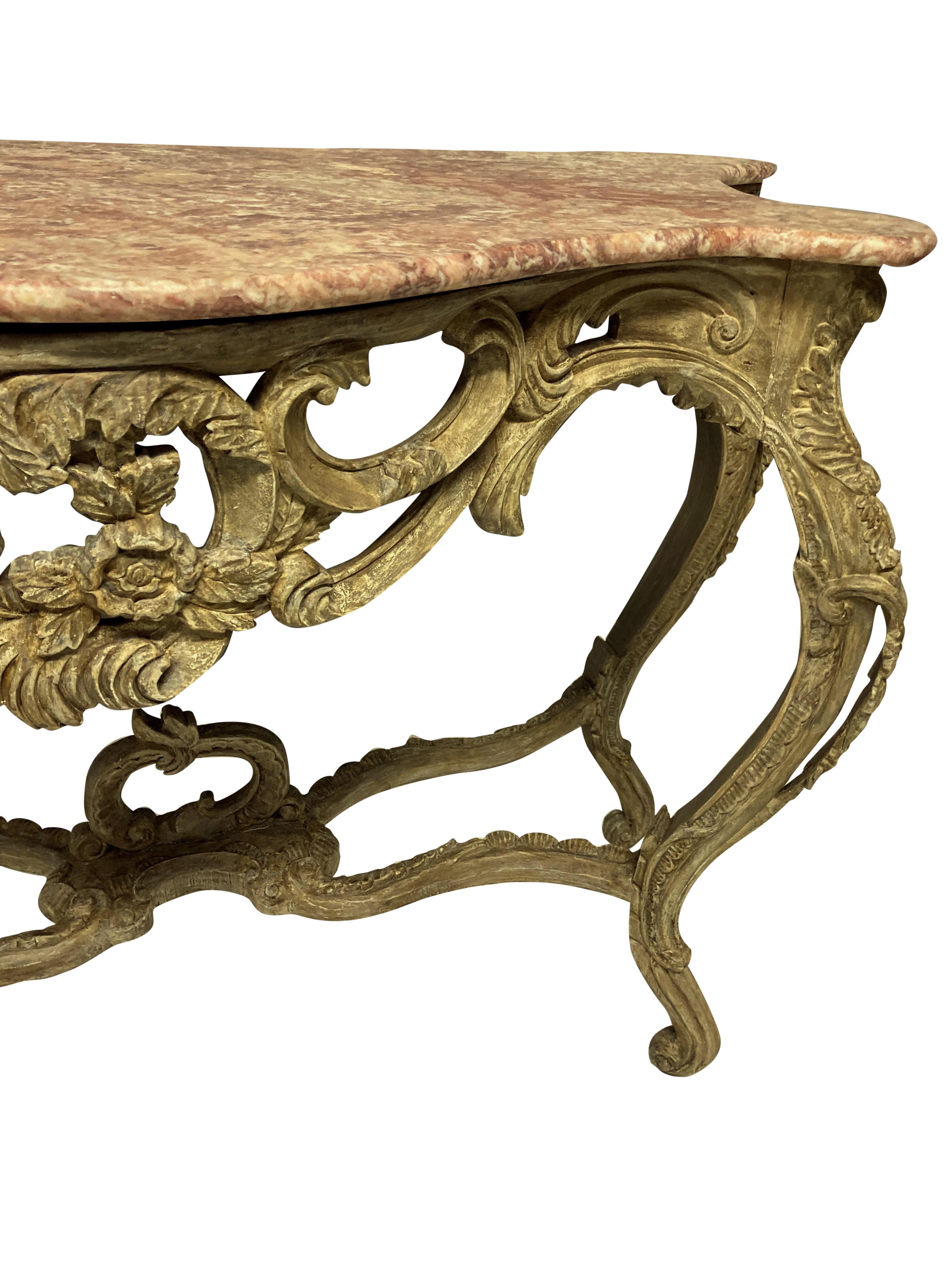 A pair of French Louis XV style console tables of good size, carved in fruitwood and painted. With shaped variegated pink marble tops.