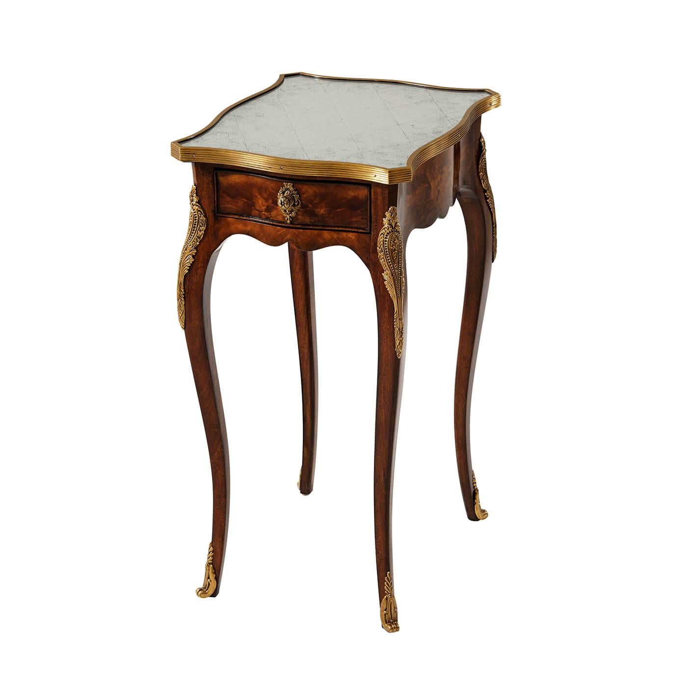 A French Louis XV style mahogany side table with fine brass mounts, the serpentine antiqued glass and brass bound top above an end drawer, on cabriole legs with sabots. The original Louis XV, circa 1760.

Dimensions: 13