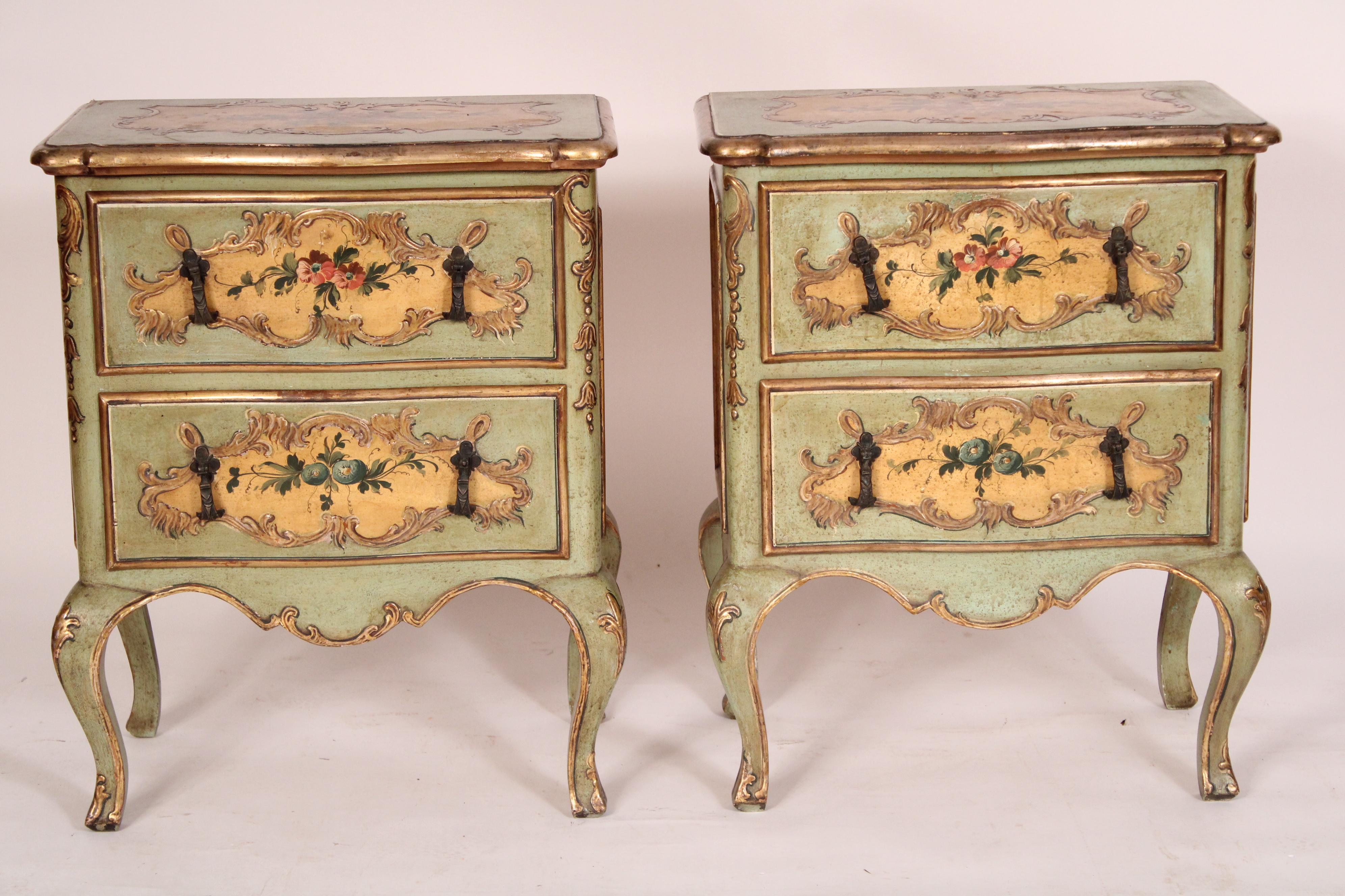 Pair of Venetian Louis XV style painted and gilt decorated commodinis, circa 1950's. The top with central floral painted decoration framed by a raised gilt cartouche, below are two drawers with floral decoration framed by raised gilt decorated