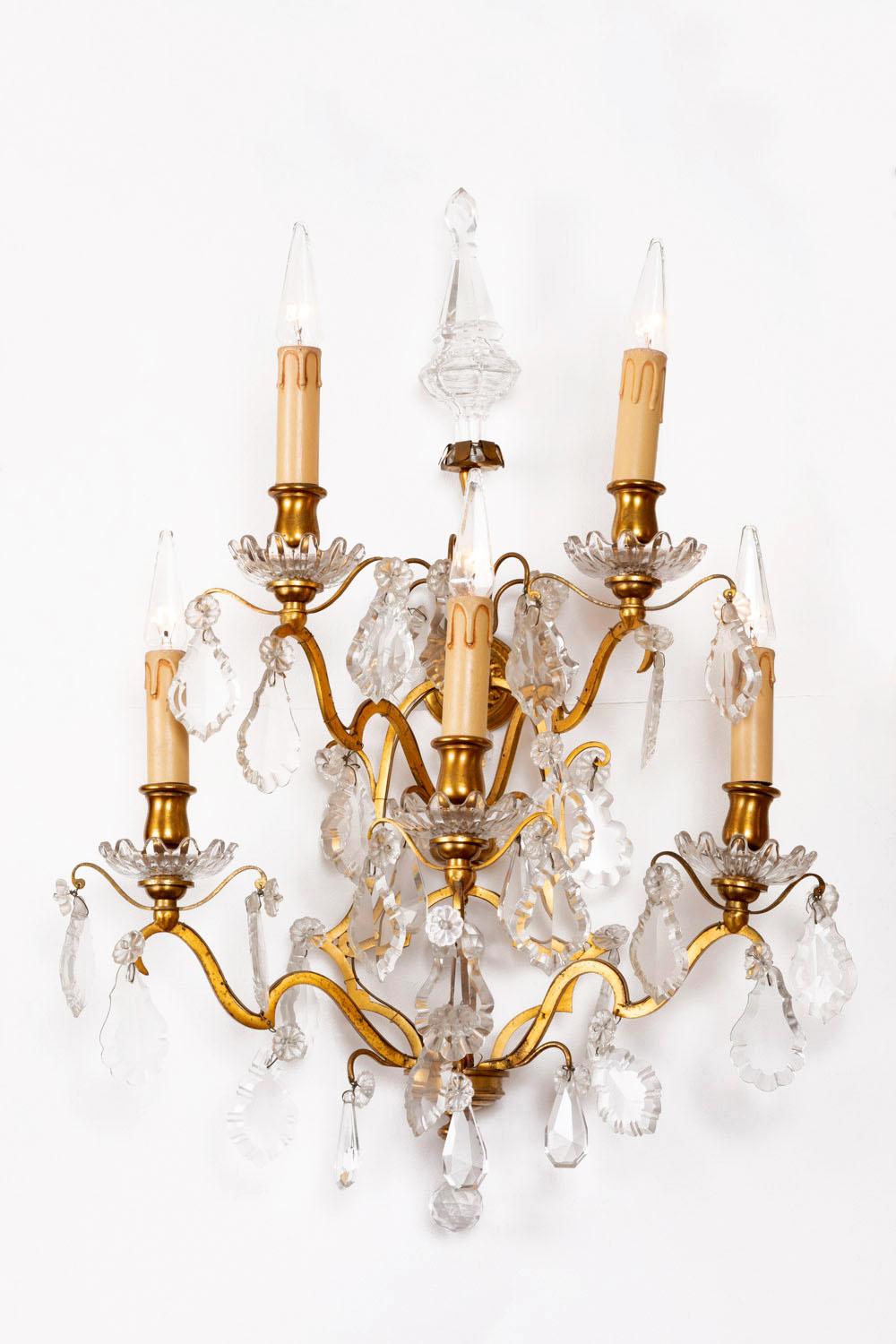 Pair of Louis XV style wall sconces with two levels and five-arm lights in gilt bronze curved shape receiving flower shaped cups topped by gilt bronze bobeches and fake candles.
Ornamentation of crystal tassels with drop, rosette and leaf shapes.