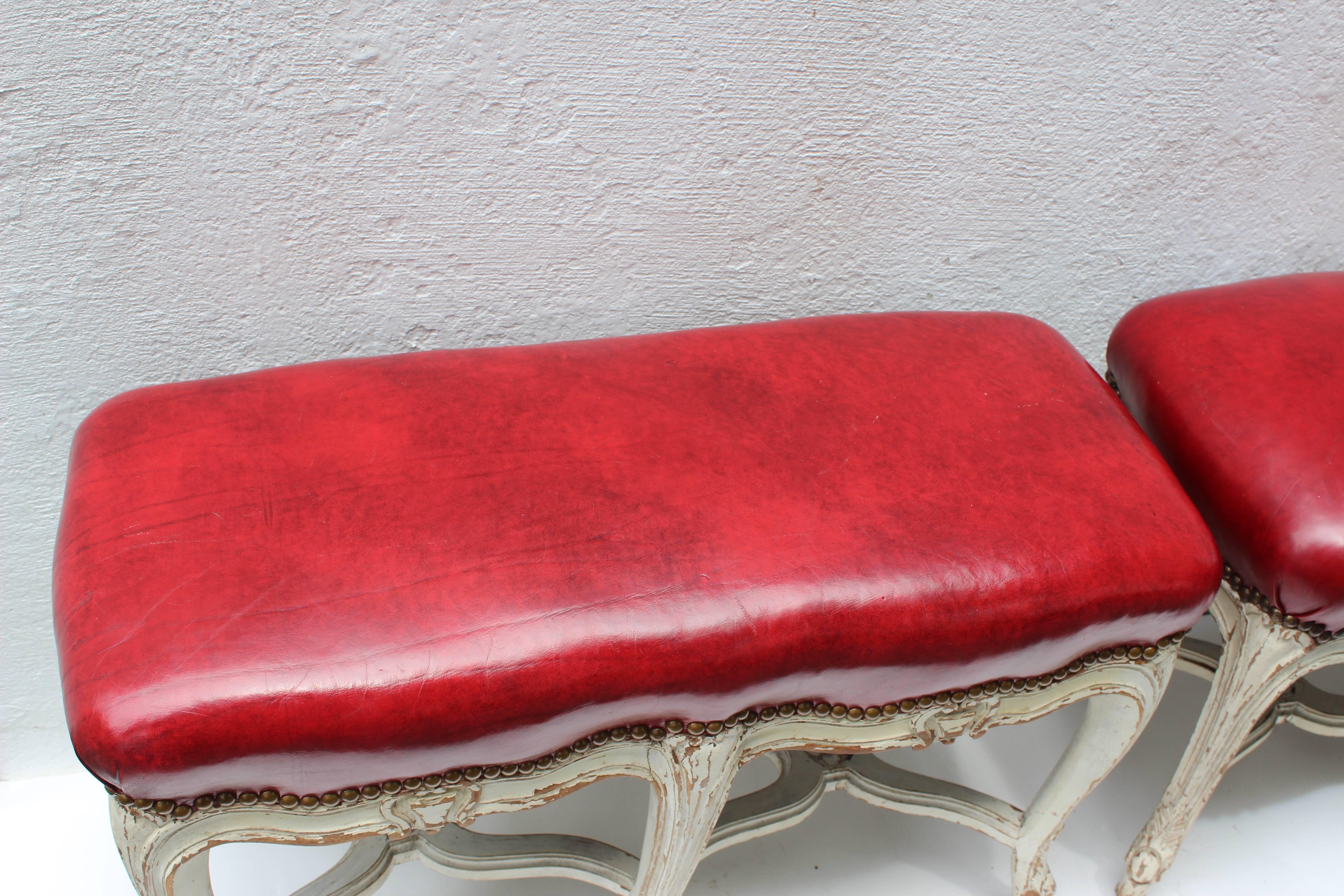 Pair of Louis XV style white painted benches upholstered in red leather.
