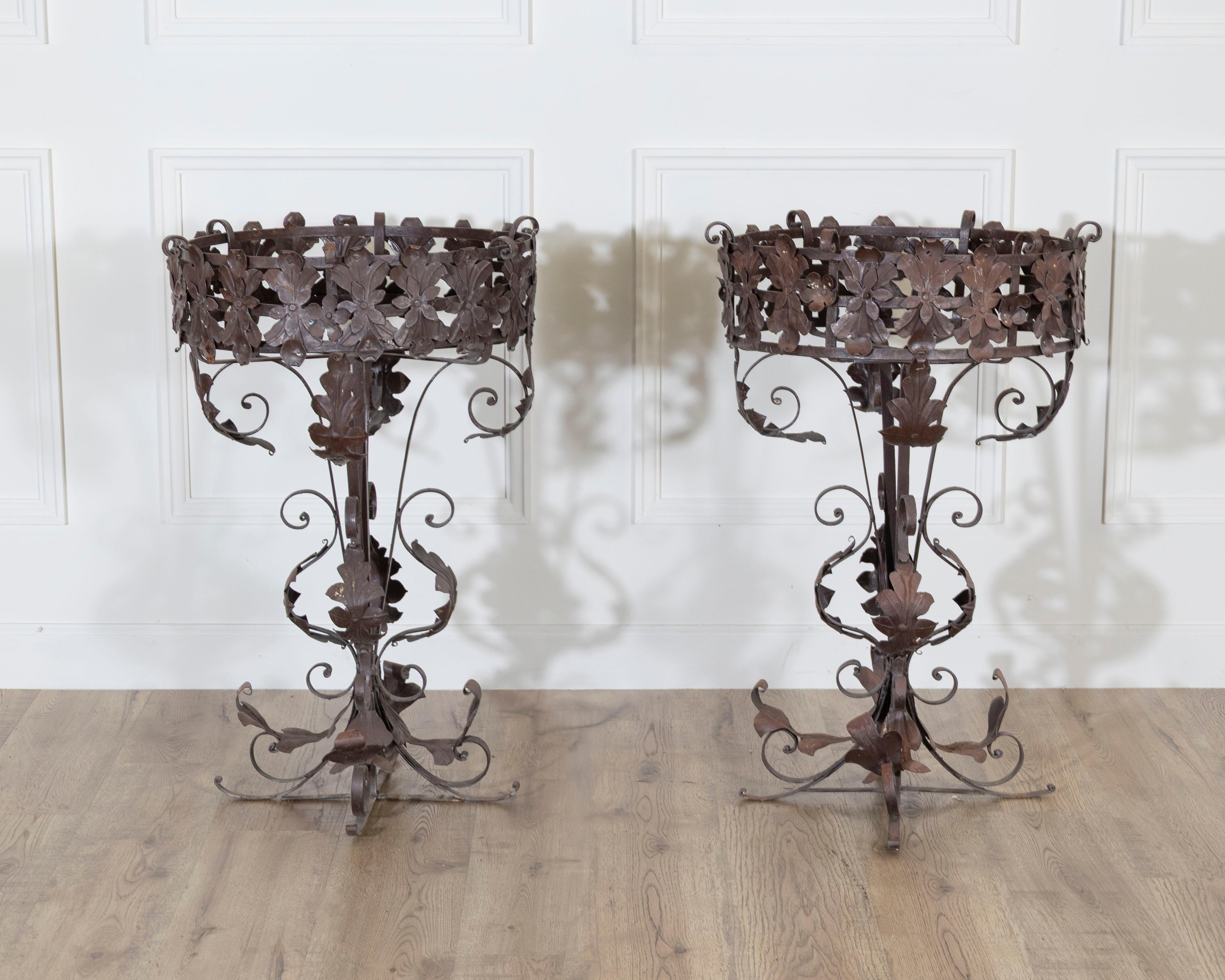 A decorative pair of Louis XV-style wrought iron planters, richly adorned with hand-forged scrolls, acanthus leaves, and floral motifs. The craftsmanship showcases the elegance and fluidity of Rococo design, where naturalistic ornamentation is