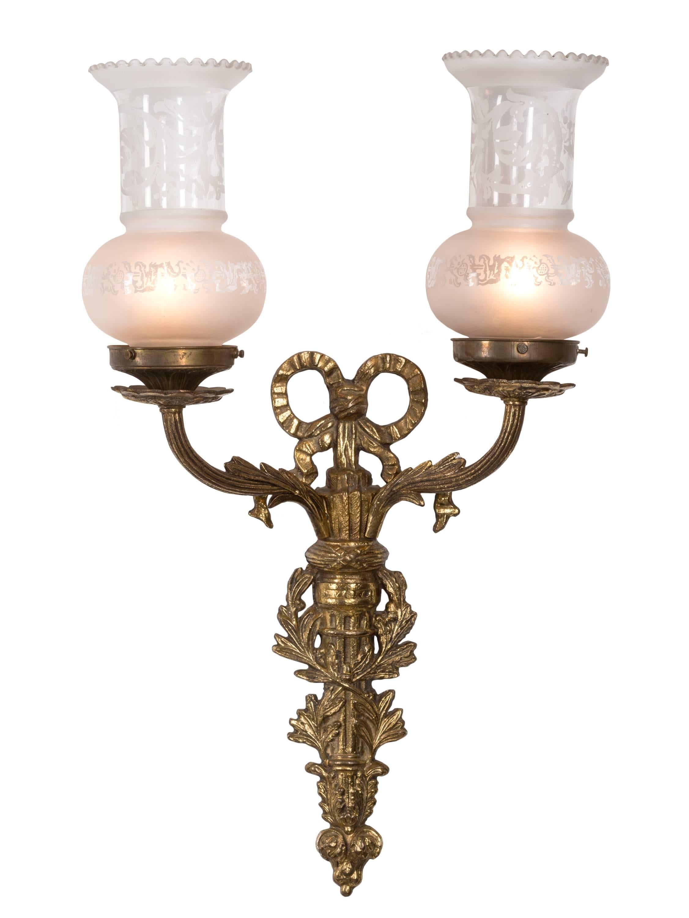 A very nice matched pair of Louis XVI style bronze wall sconces, each having two electric sockets with frosted glass chimneys in 
