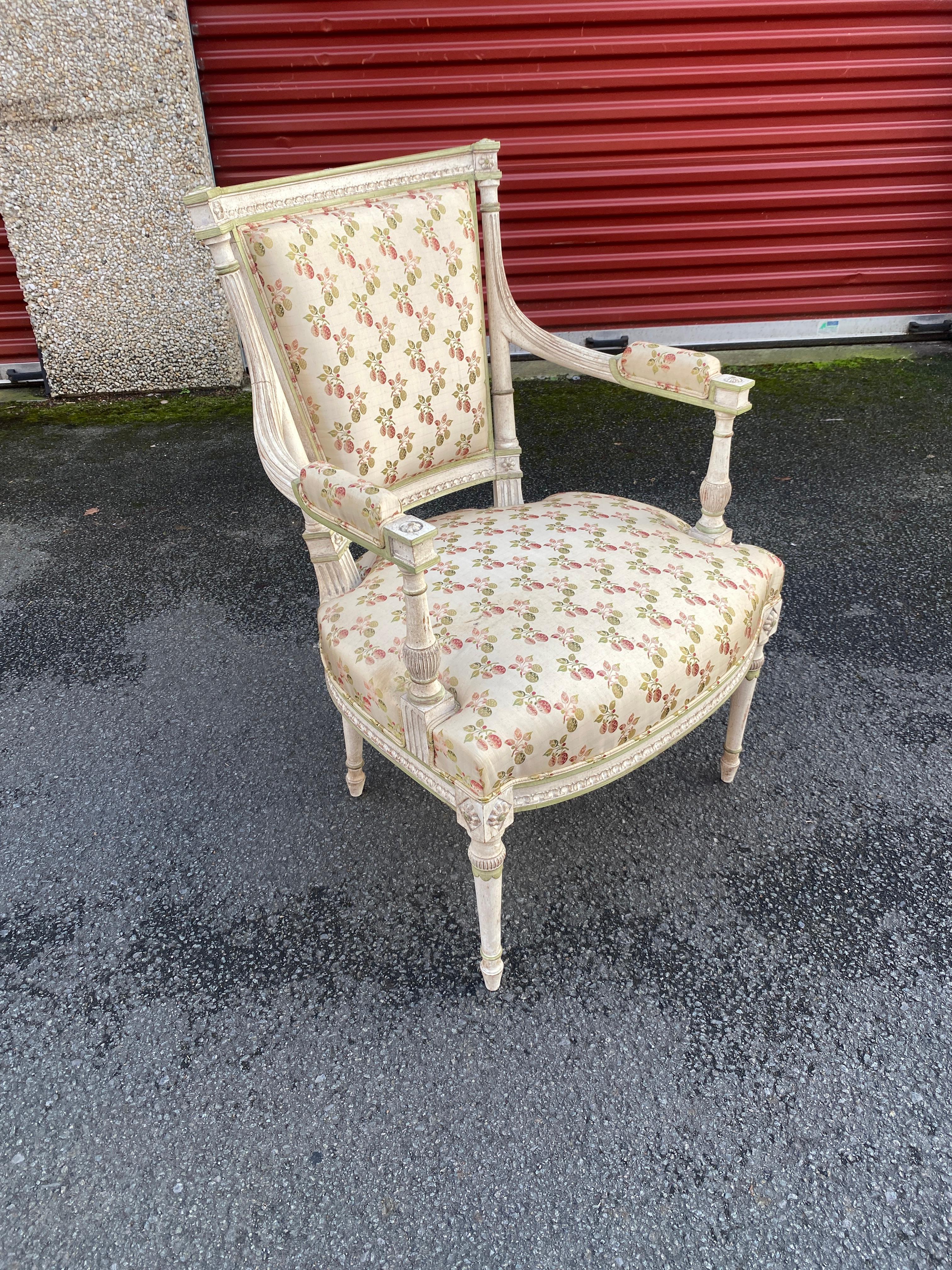 Paire de fauteuils à dossier incurvé en bois relaqué crème et rechampi vert, le dossier à colonne détachée surmontée de petites fleurs, les consoles d'accoudoir en balustre reposant sur des pieds fuselés. Style Louis XVI. 
Revêtements et tissus