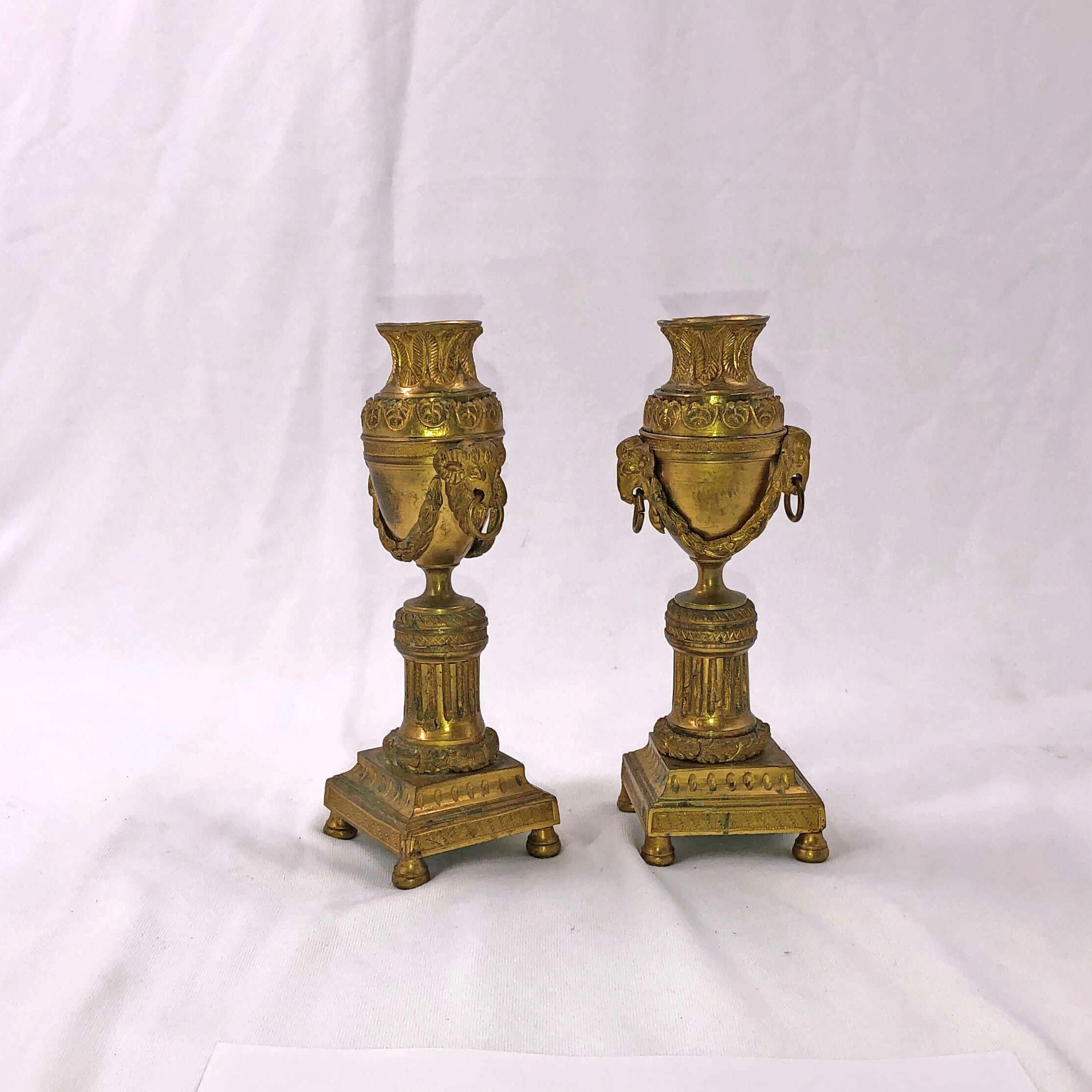 A pair of French bronze Cassollette with urn form chased ram's heads with garlands and a fluted pillar and raised on a chased square base with bunn feet.