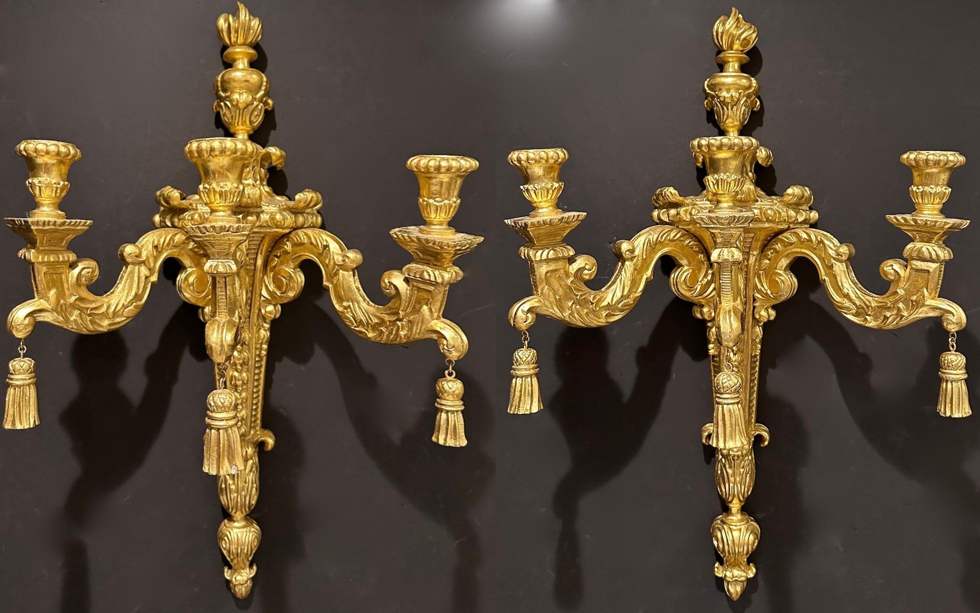 Large and impressive carved and gilt wood 3- arm wall sconces in the Louis XVI style. Urn and flame for top with tassels hanging from each arm.
These sconces are currently NOT wired for electricity, but could be.