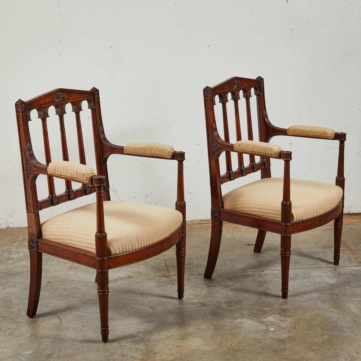 Pair of Louis XVI style hand-carved mahogany fauteuils by George Jacob, a distinguished designer under the reign of Napoleon I. Newly reupholstered in a creamy gold-toned fabric, the chairs have a unique architectural schema to their decorative