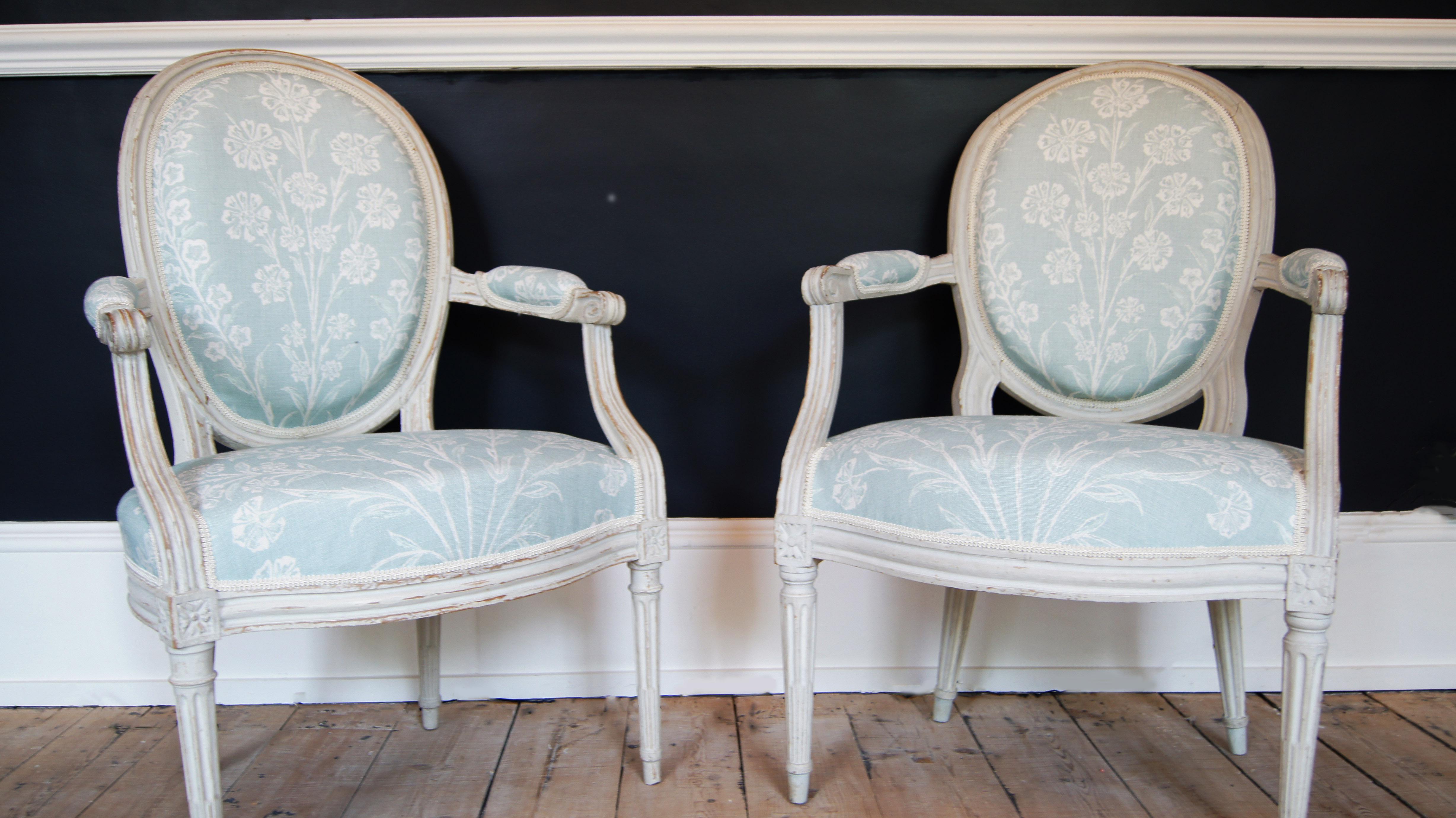 A pair of French carved and painted Louis XVI fauteuils, with oval backs, seats and armrests upholstered in Chelwood fabric, designed by Nina Campbell. With grey/white painted frames. Both chairs bears the mark of Barthelemy Denis Chardon, Paris,