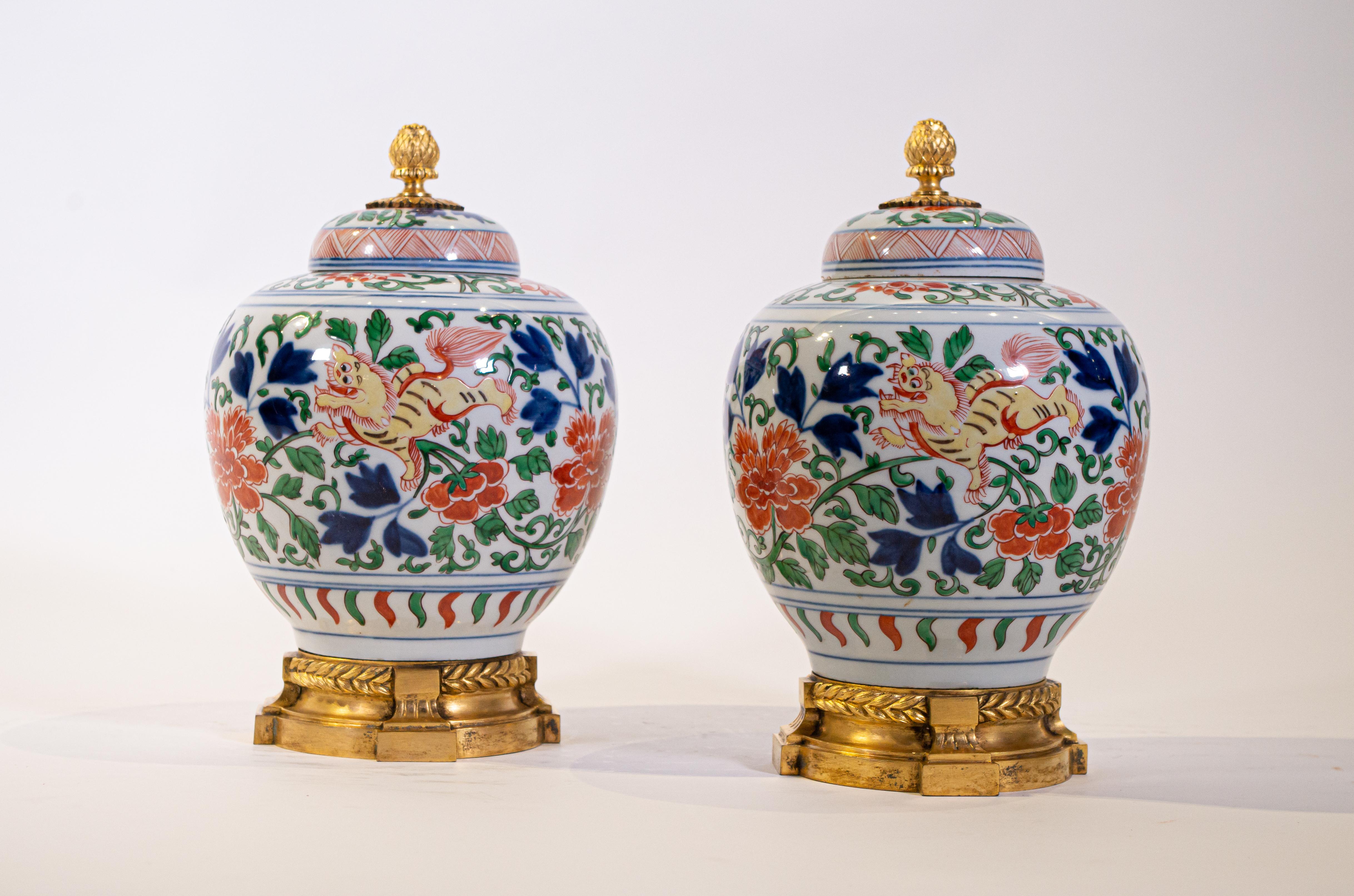 A fabulous and very decorative pair of Louis XVI style dore bronze mounted Chinese porcelain Wucai covered urns. These are truly a beautiful pair of urns, with wucai colors, which include green, red, blue, orange, yellow and a white ground. Each has