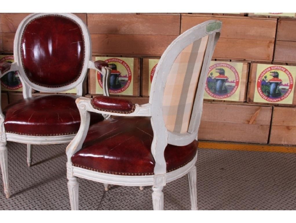 From the iconic Carlyle Hotel in New York City, a pair of Louis XVI fauteuils with distressed white paint and red leather seat and backrests, balloon backs ending in shaped seat with flanking scroll carved arms, supported on fluted and turned