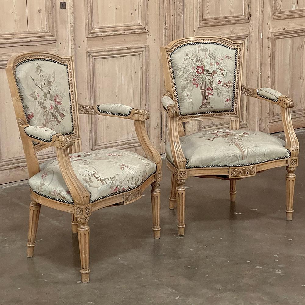 Pair of Louis XVI French Aubusson Tapestry Fruitwood Armchairs was hand-crafted from solid apple wood in one of the more intriguing interpretations of the Louis XVI style.  This pair of armchairs retain the light, warm tones of the wood, hand-carved