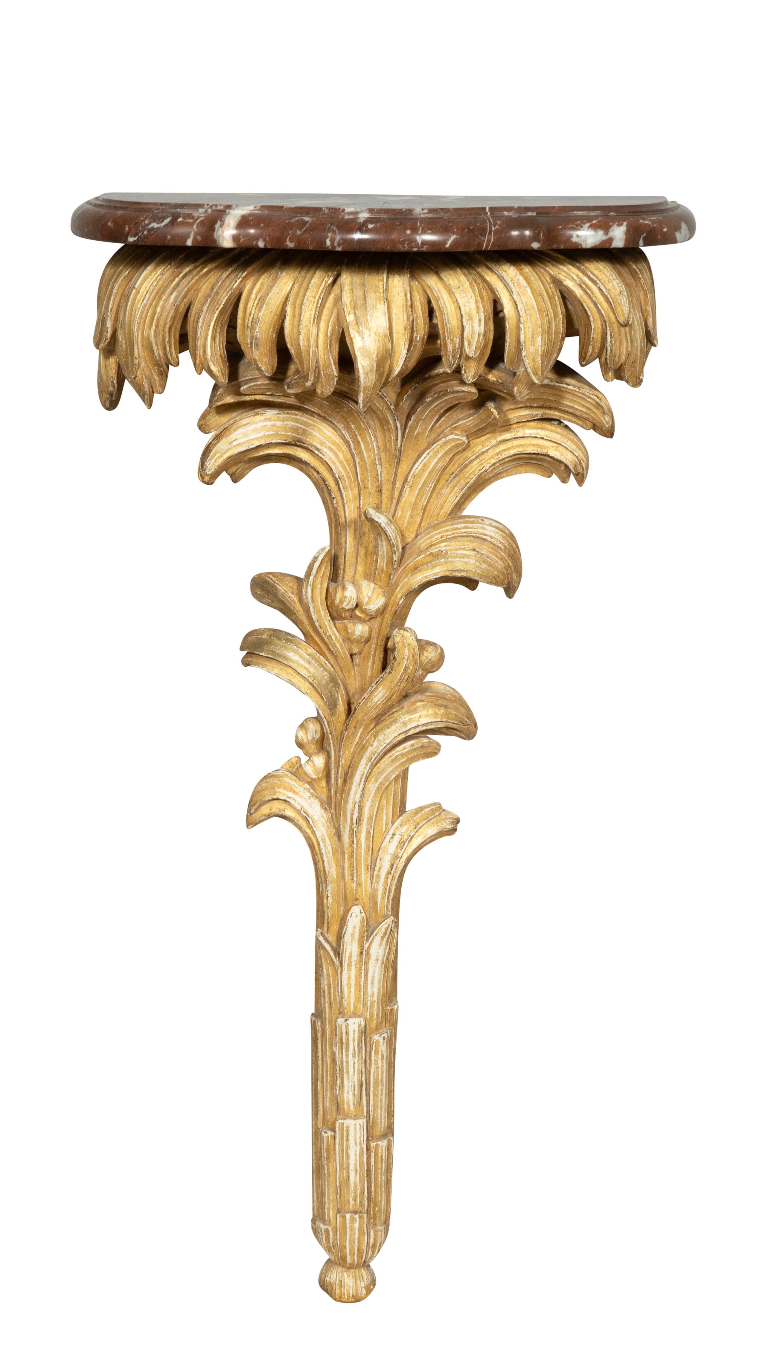 Each with a removable brown and white serpentine marble top supported on a gessoed and water gilded carved oak and stylized palm leave brackets. The gilding is dry and subtle with great patina and condition. Each is individually carved showing