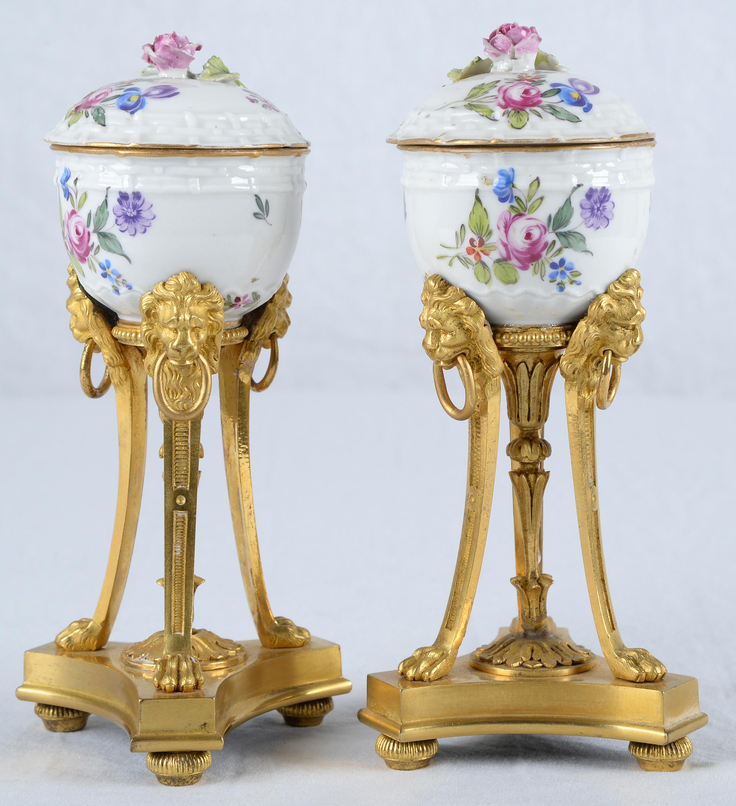 Ogni vaso di porcellana è delicatamente decorato con fiori e poggia su una base a tripode squisitamente cesellata con teste di leone.
Questi vasi in porcellana di Chantilly venivano impreziositi a Parigi con montature neoclassiche che assomigliavano