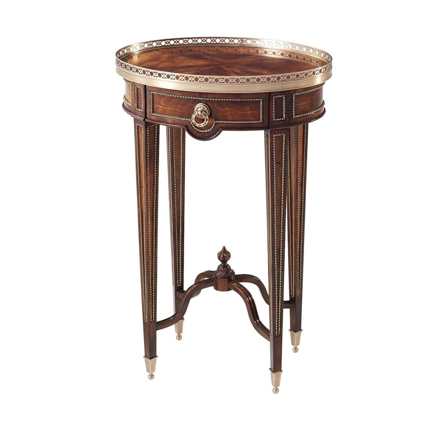 A French Louis XVI style mahogany oval end table with fine brass mounts, the brass galleried oval top above a frieze drawer on paneled square tapering legs with brass cappings joined by an 'X' stretcher.

Dimensions: 19.5