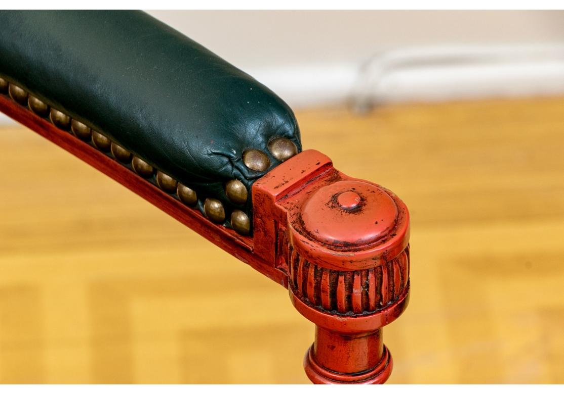 Una notevole coppia di sedie da salotto molto basse in stile francese con una verniciatura di grande effetto. Coppia di fauteuil decorati a vernice con schienale ovale in canna e seduta in pelle verde scuro a contrasto con manchette abbinate. Le