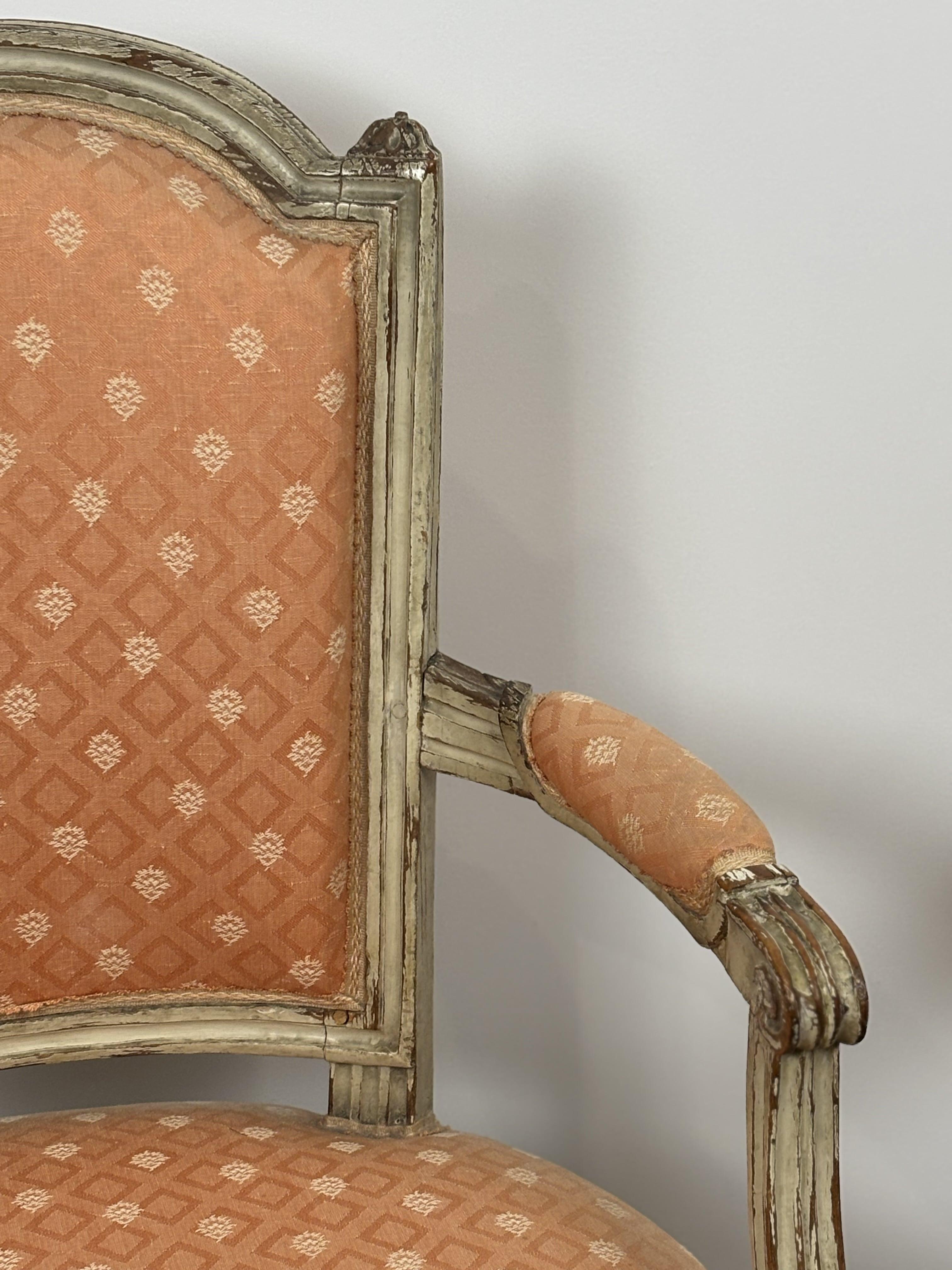 Elegant pair of armchairs with gendarme hat backs in molded and re-lacquered gray wood. 
They rest on fluted tapered legs, the front ones rudenté. 
Louis XVI period.