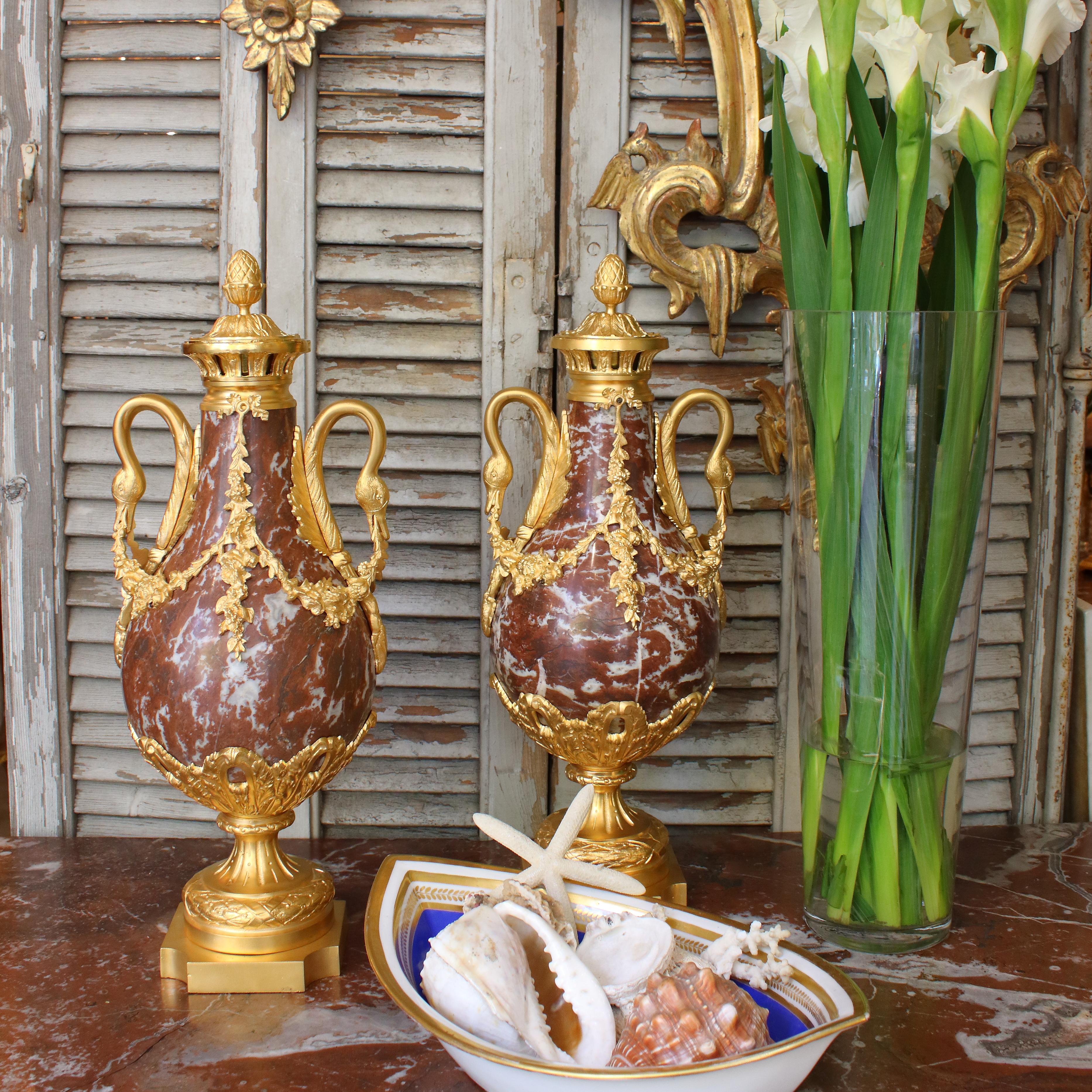Pair of 19th century Louis XVI style solid 'Rouge Languedoc' marble and gilt bronze-mounted baluster-shaped decorative vases. Standing on a rectangular plinth with concave corners and a round neoclassical foot. The finely chiseled and