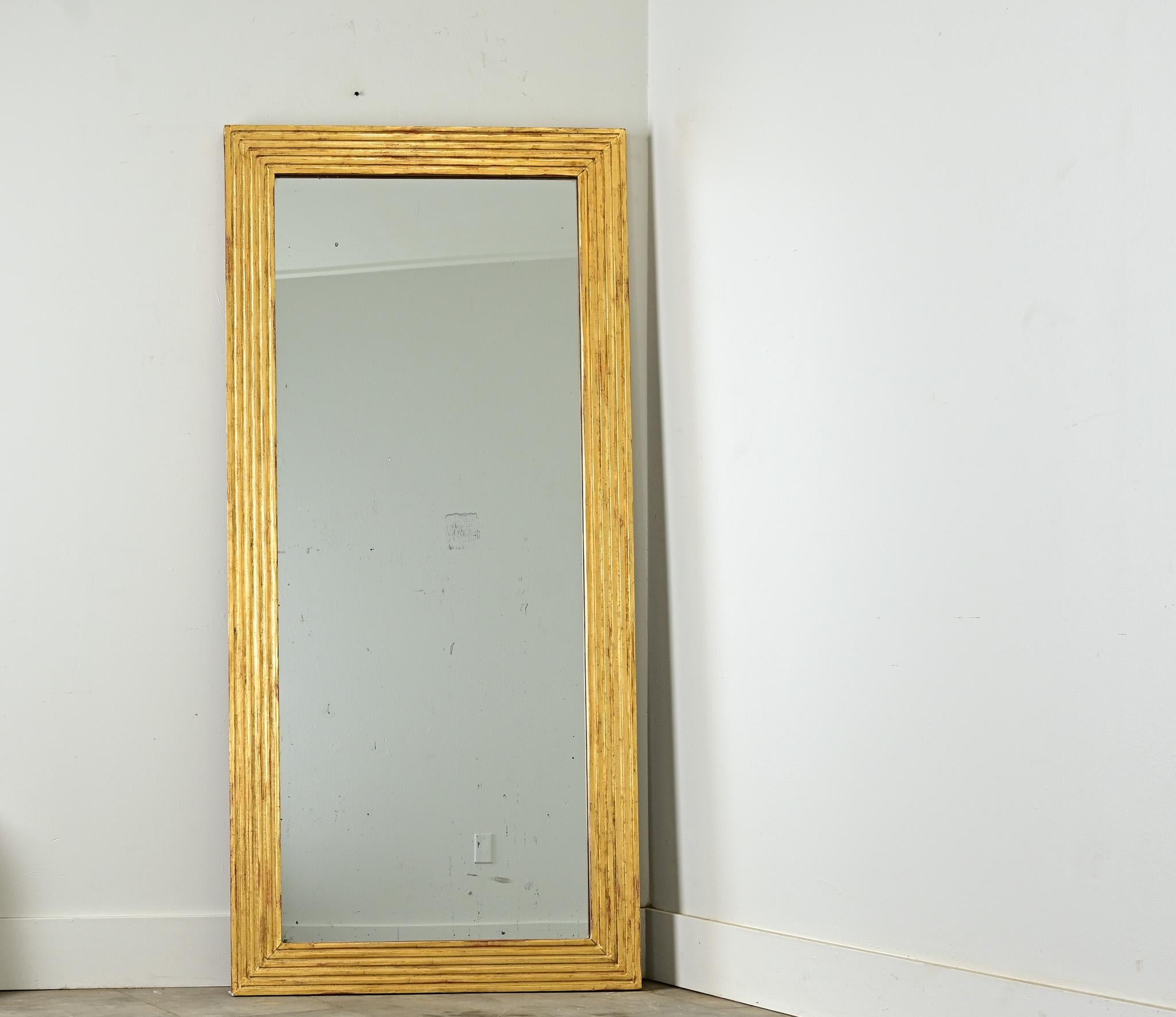 Flat, reeded molding is an ideal surface area to reflect the luster of gold leaf on this exciting pair of Louis XVI mirrors. Symmetrical for mounting in either direction, these narrow and linear mirrors would look sharp in any room (or two). The