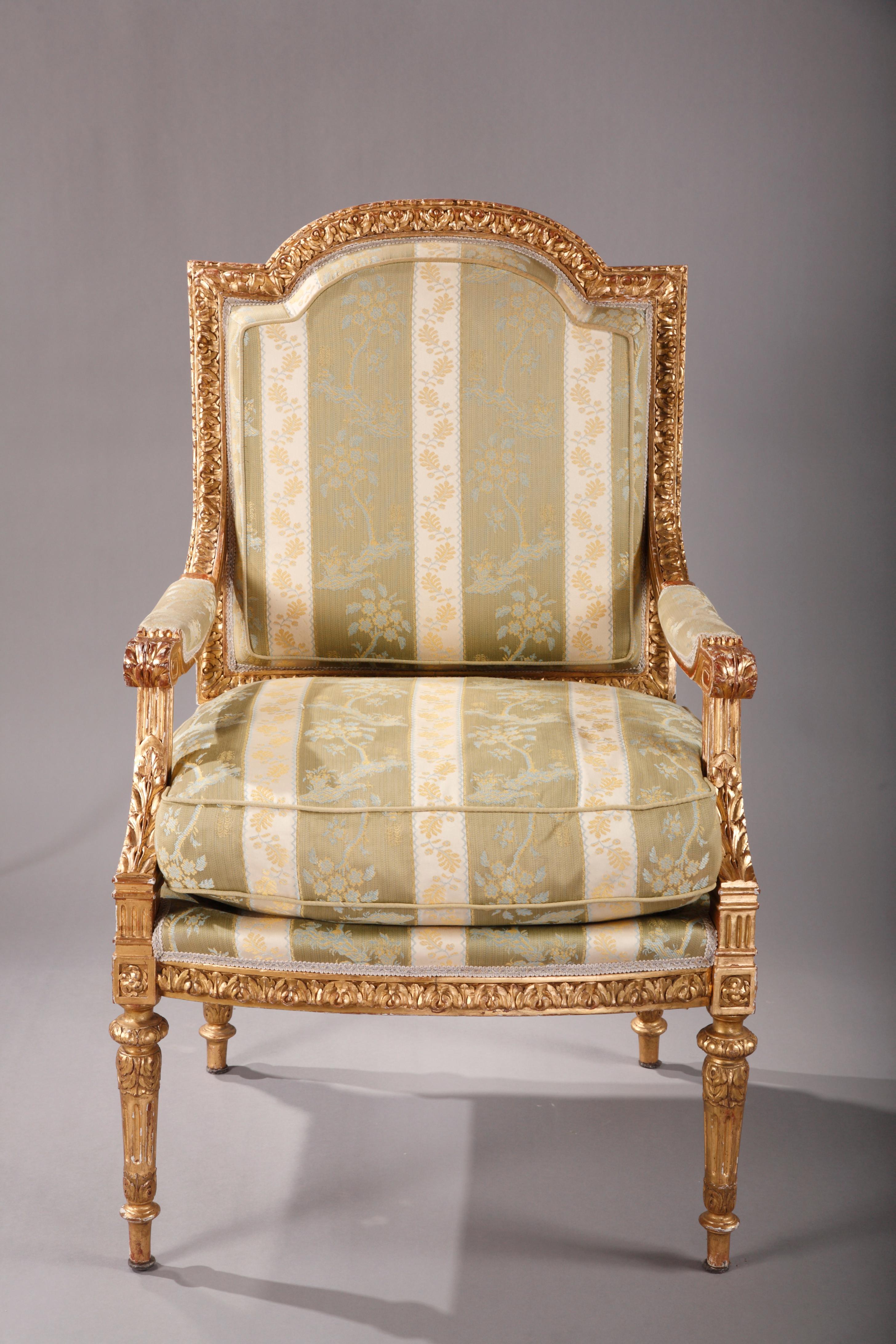 A very fine pair of Louis XVI style carved and gilded wood armchairs, with the back in the form of an inverted gendarme's hat ; the seatback and the seat belt are delicately carved with water leaves, acanthuses and rosettes. Reposing on tapered and