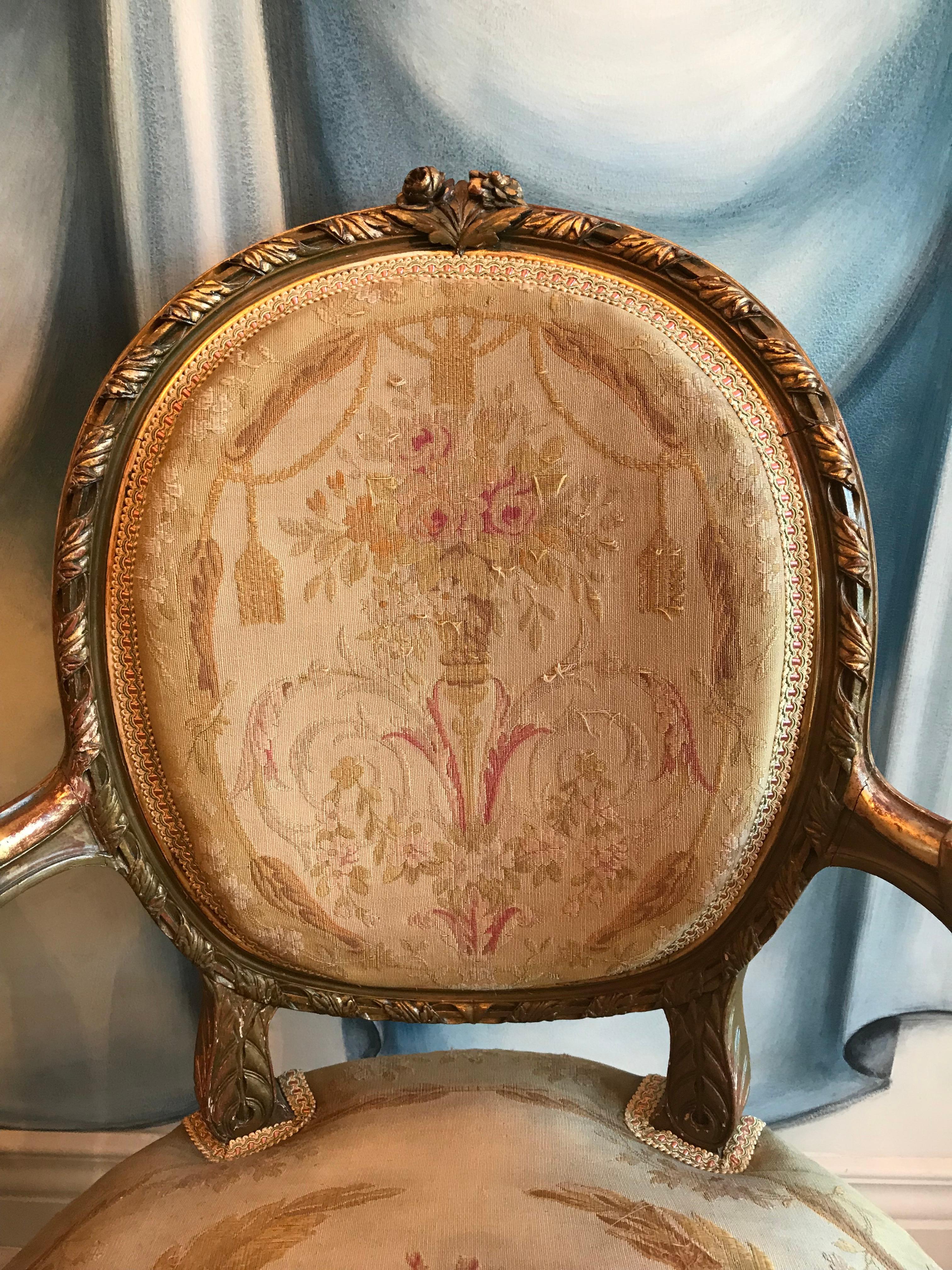 Paire de fauteuils Louis XVI, en bois doré avec de beaux détails sculptés. Tissu gobelin original exquis, le gimp a été remplacé. En bon état.
