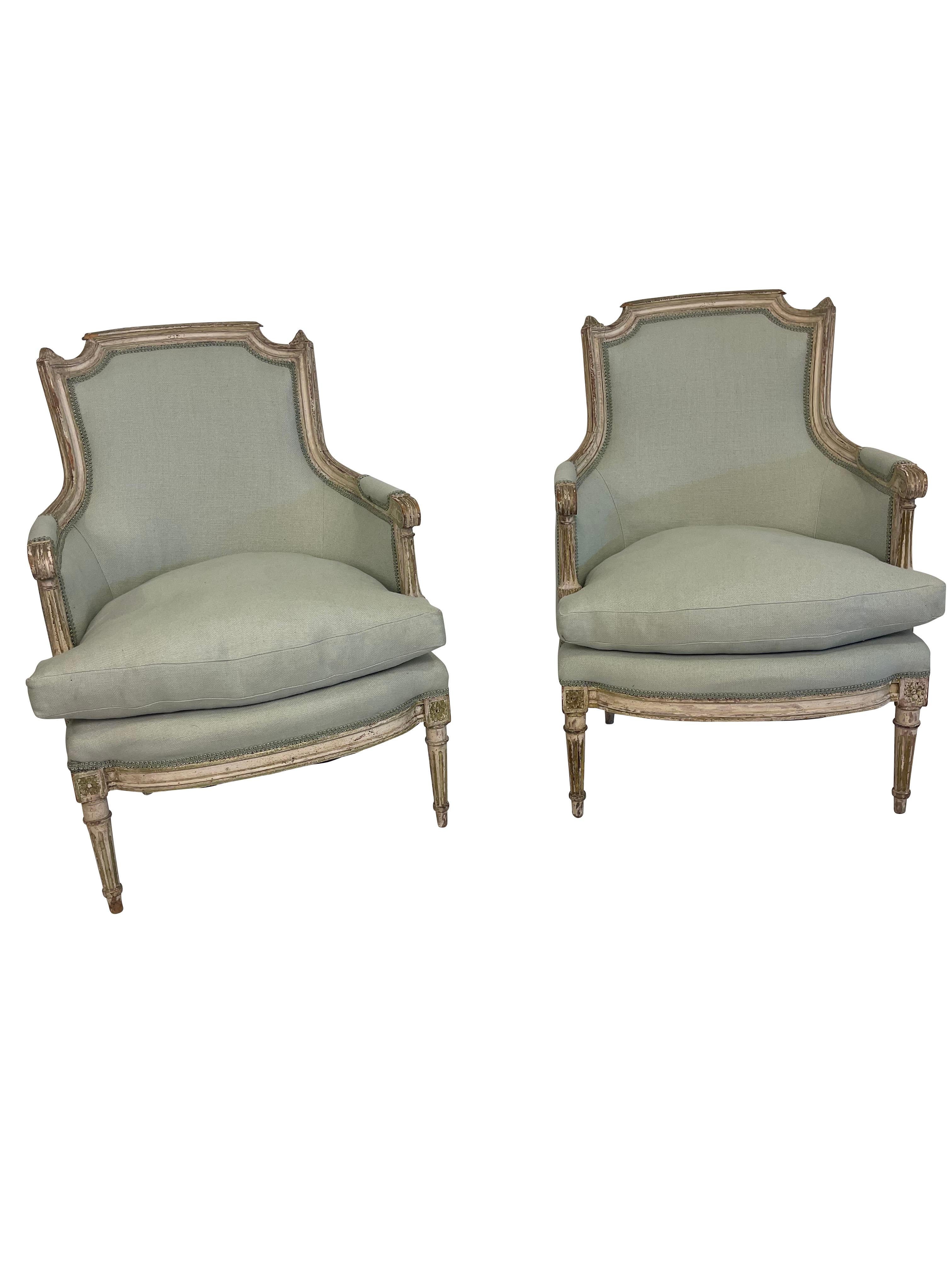 A pair of stunning French Louis XVI bergères, newly upholstered in a (blue/green) seafoam linen and gimp trim, with separate down-stuffed seat cushions. The chair frames are grey-painted, with 