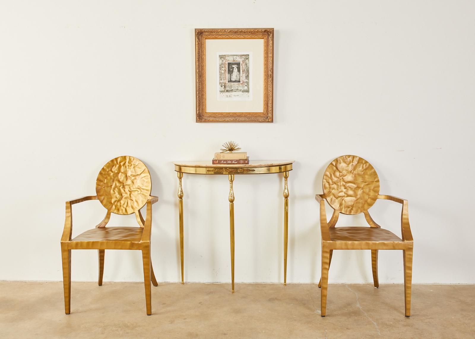 Rare, matched pair of elegant brass demilune console tables featuring marble tops and bronze mounted frieze. The skirted tops are supported by long, fluted tapered legs with a neoclassical vase form on top decorated with acanthus scrolls. The frieze