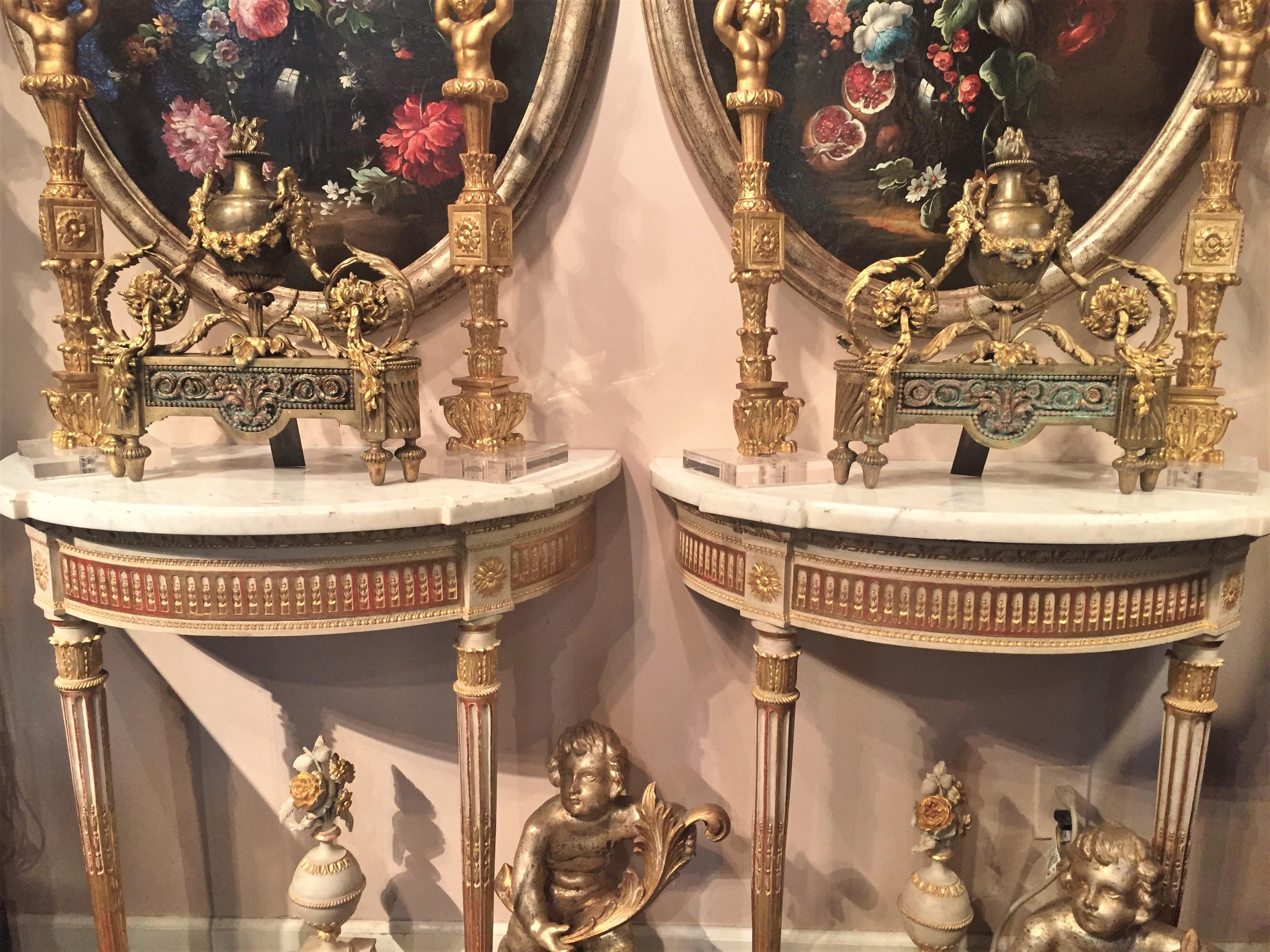 Pair of Chenets or andirons, bronze and gilt bronze. Typical neoclassical style urns with floral festoons and foliate scrolls on fluted 
base. Contrasting finishes, patinated, gilt decorated, polished all to give effect. Distressed finish with