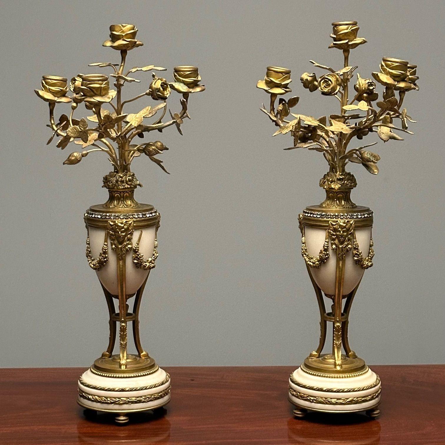 Pair of Louis XVI Style Gilt-Metal and White Marble Four-Light Candelabra

Each with a 'jeweled' urn-form standard continuing to hoof feet, raised on a circular base, on squat toupie feet. The pair with satirical masks with wreath bodies.

Height: